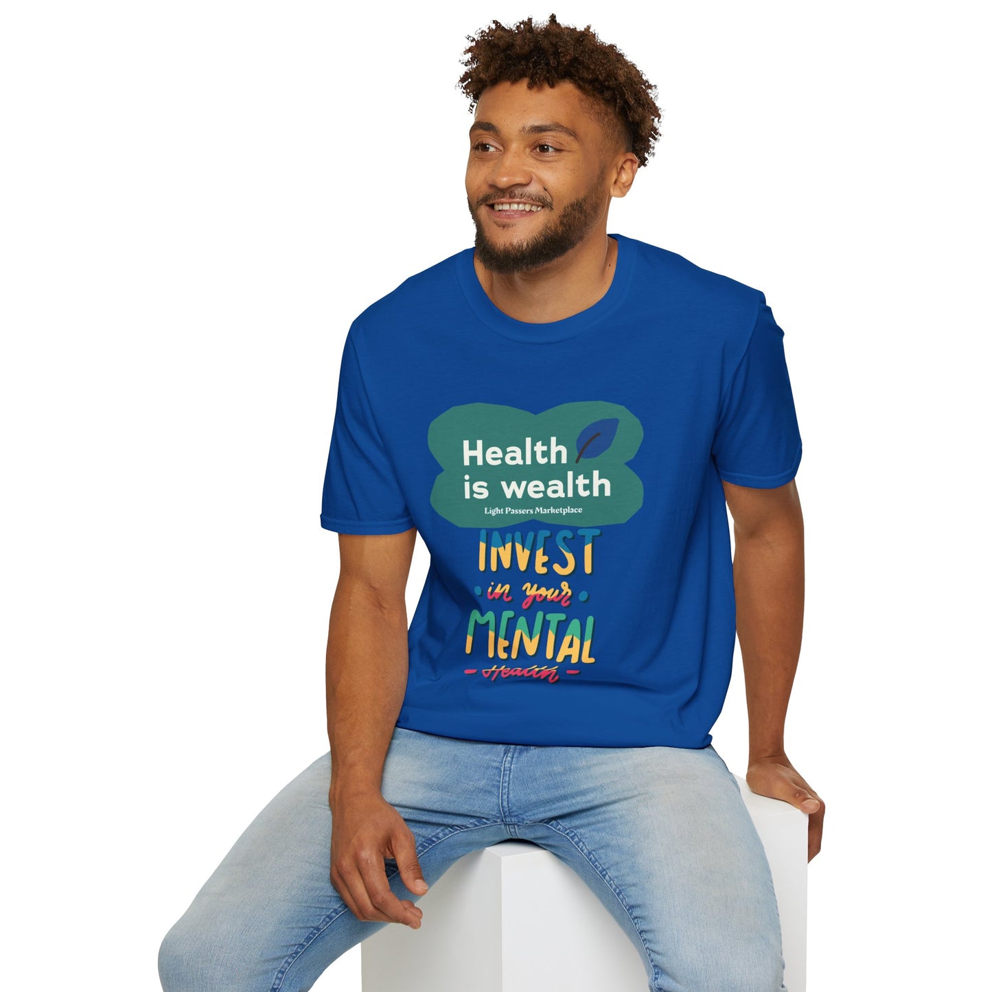 A man in a blue shirt sits on a cube, showcasing the Invest in Mental Health Unisex T-shirt. Made of soft 100% cotton, featuring twill tape shoulders for durability and a ribbed collar.