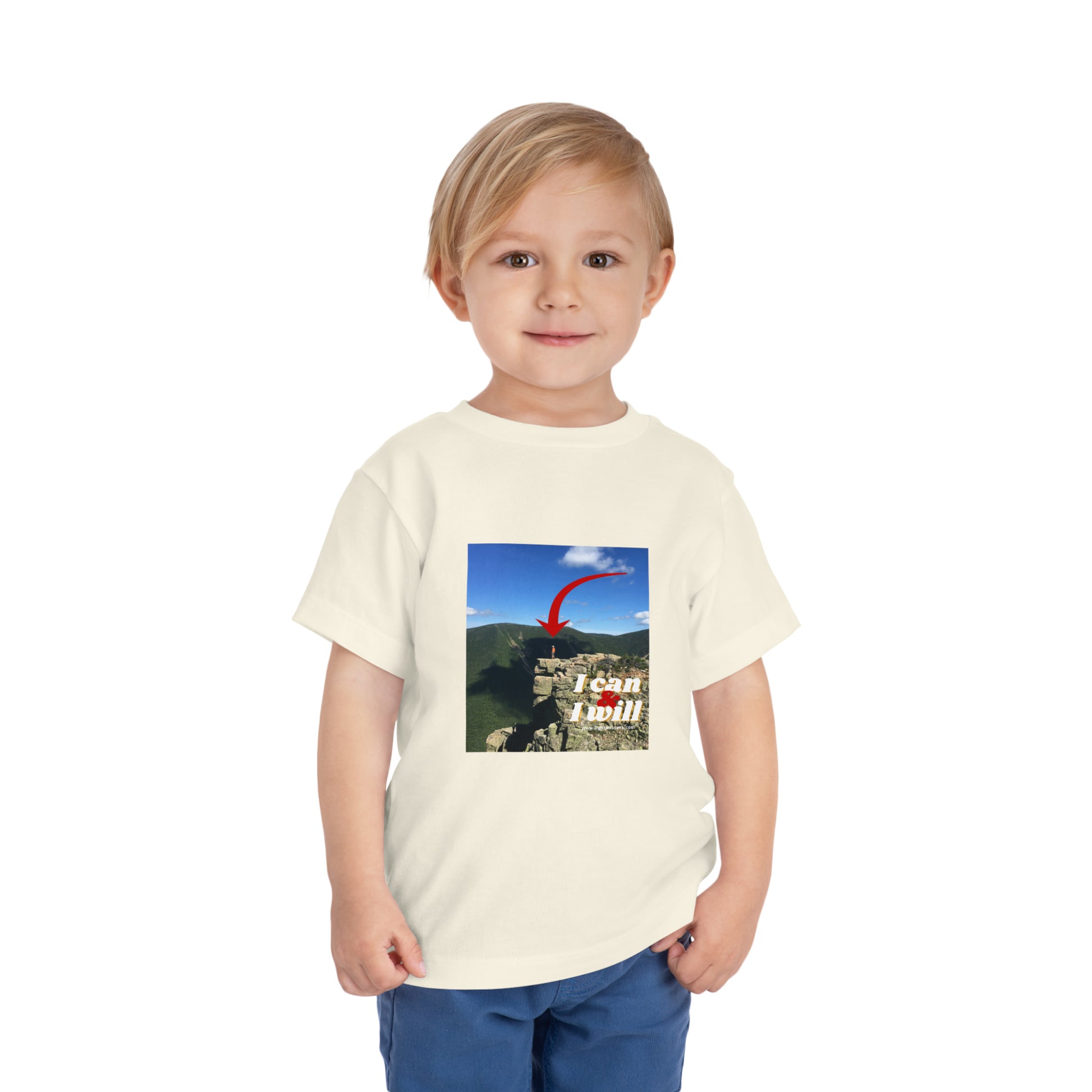 Toddler in white I Can and I Will tee, close-up of face, standing on cliff. 100% Airlume combed cotton, tear-away label, 3.9 oz fabric.