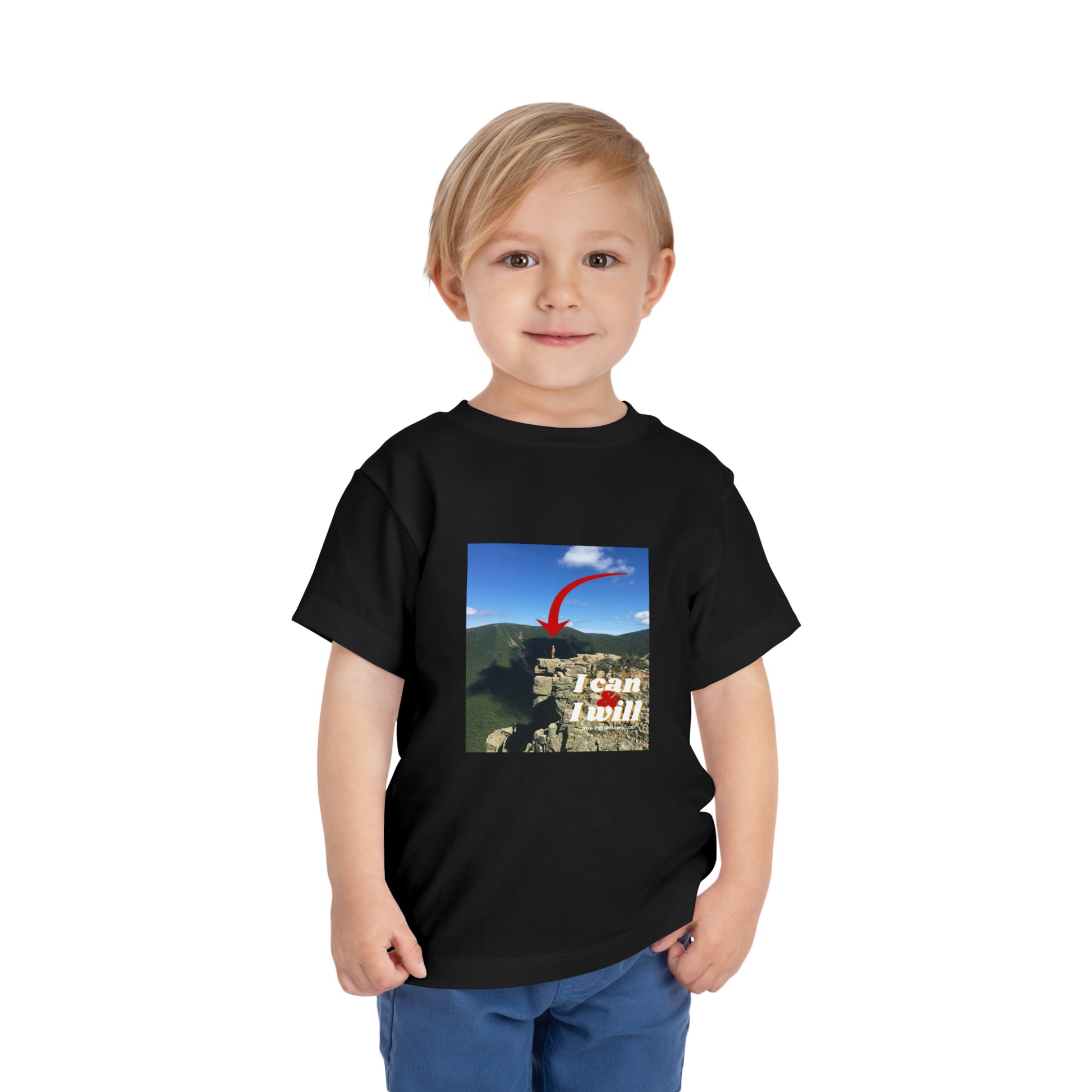 A determined boy in a black I Can and I Will hiking toddler t-shirt, standing confidently. Made of 100% Airlume cotton, tear-away label for comfort.