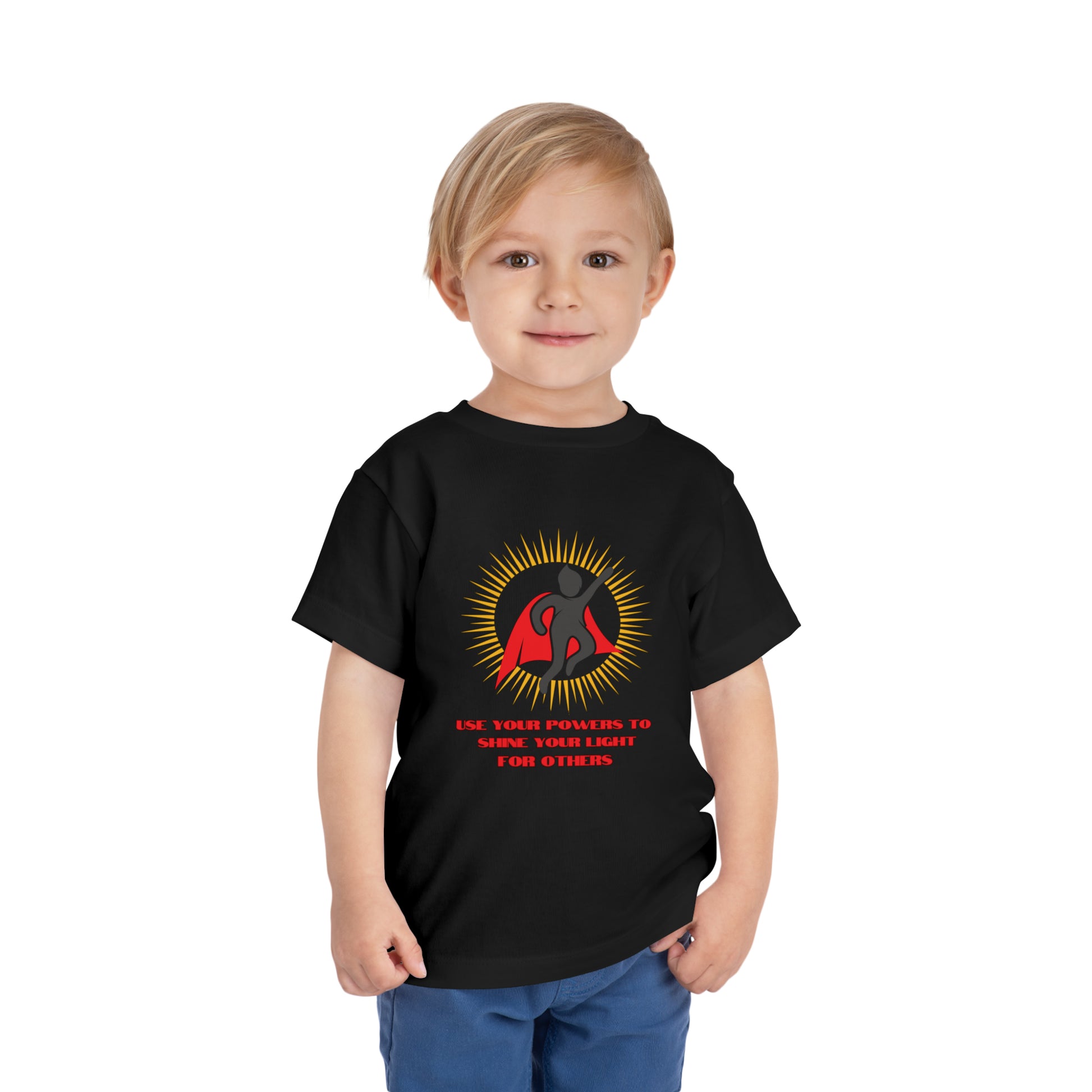 A toddler wearing a black Use Your Powers t-shirt, featuring a superhero logo. Made of 100% Airlume combed cotton, tear-away label for comfort.