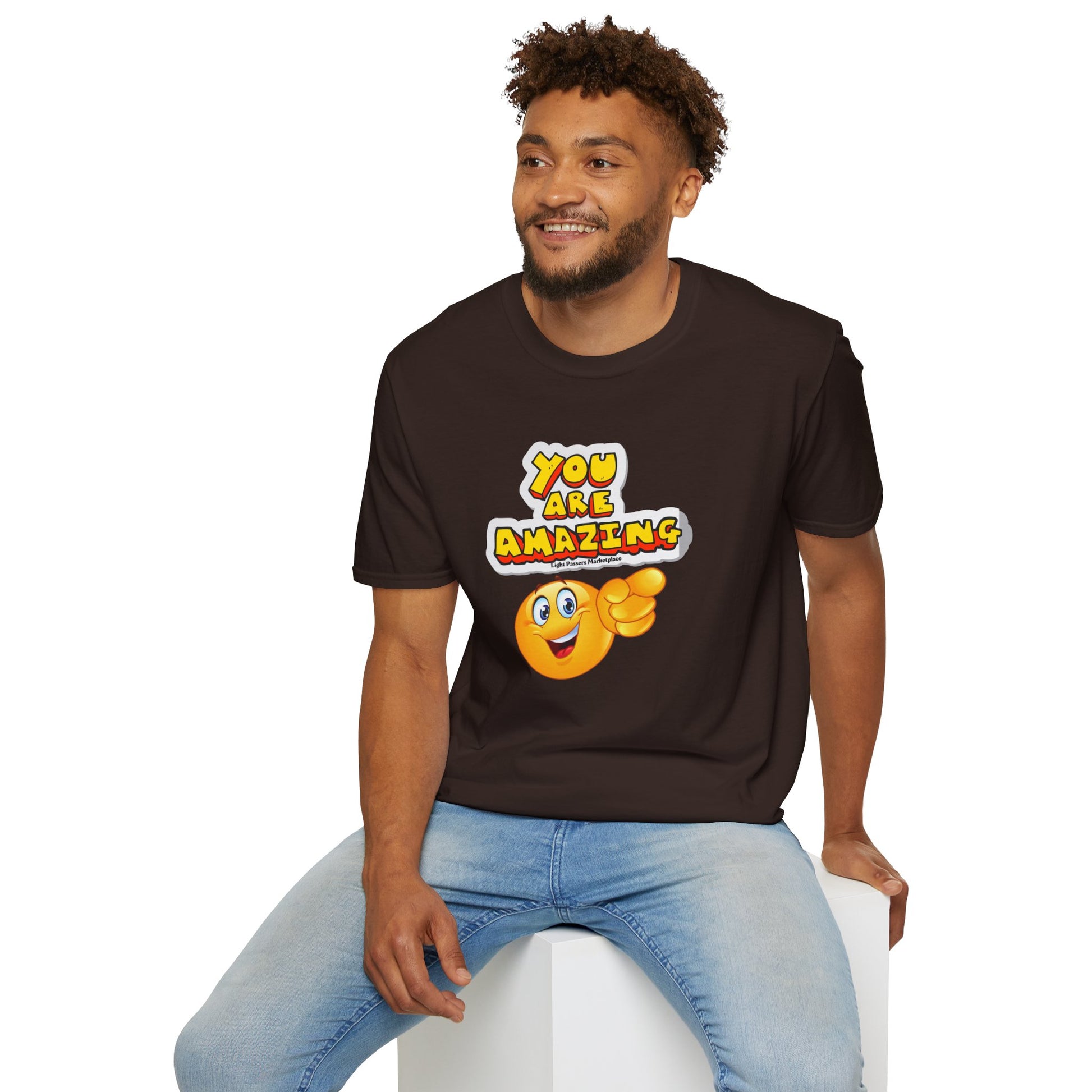 A man in a brown shirt sits on a chair, a yellow emoji points at the camera. Unisex soft-style t-shirt made of 100% ring-spun cotton, featuring twill tape shoulders and ribbed collar.