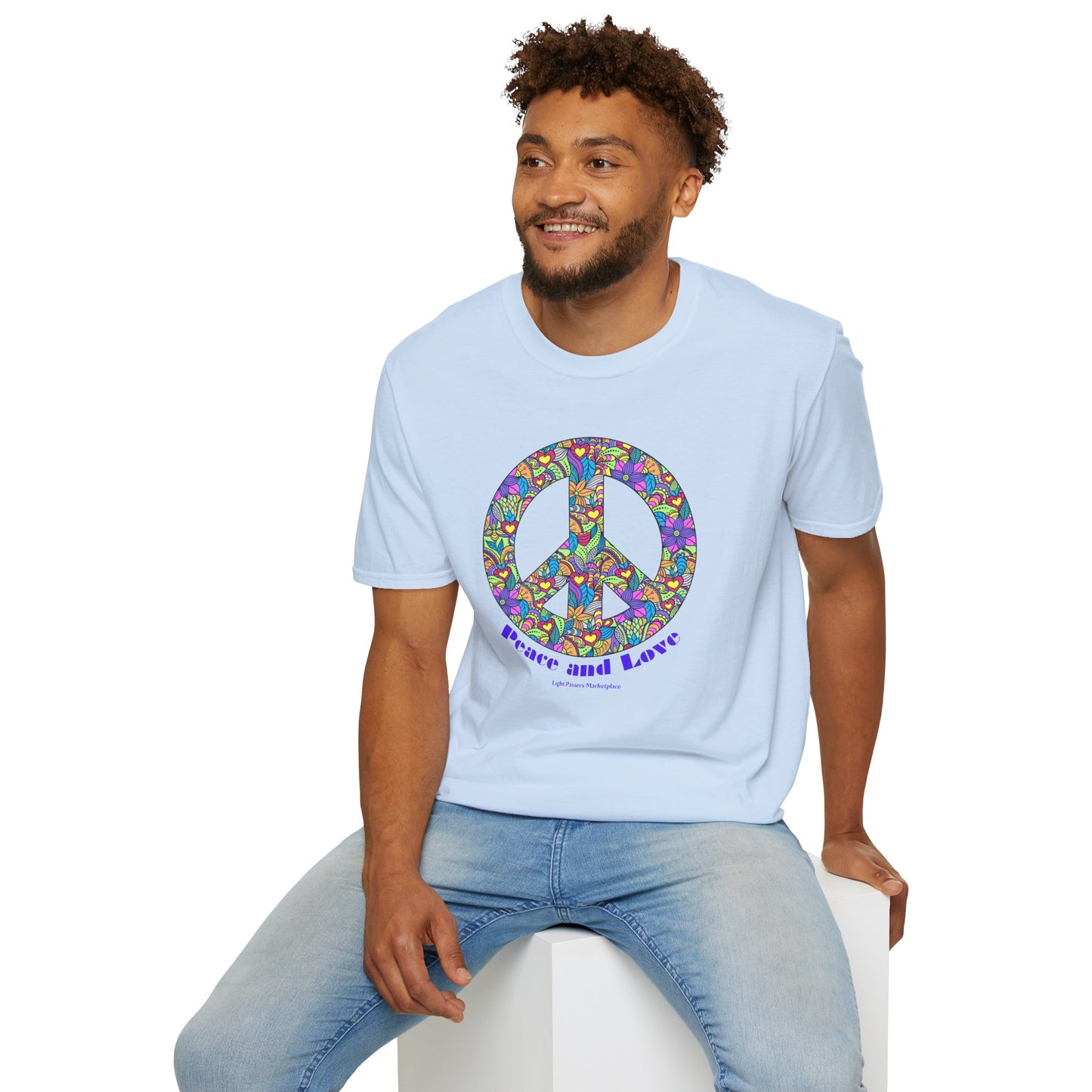 A man wearing a white Peace sign with flowers Unisex T-shirt, sitting on a cube. 100% cotton, twill tape shoulders, no side seams, ribbed collar. Ethically made, lightweight, versatile style.