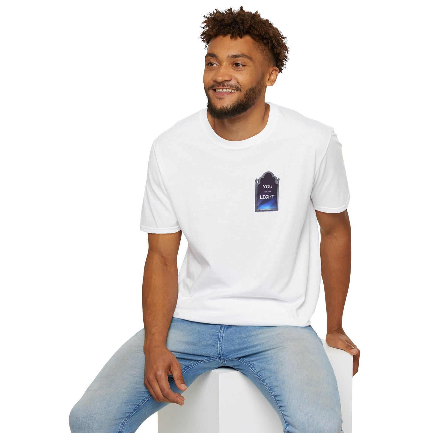 A man in a white shirt sits on a cube, showcasing YOU ARE THE LIGHT small Mirror Unisex T-shirt. Casual, heavy cotton tee with smooth surface for vivid printing.