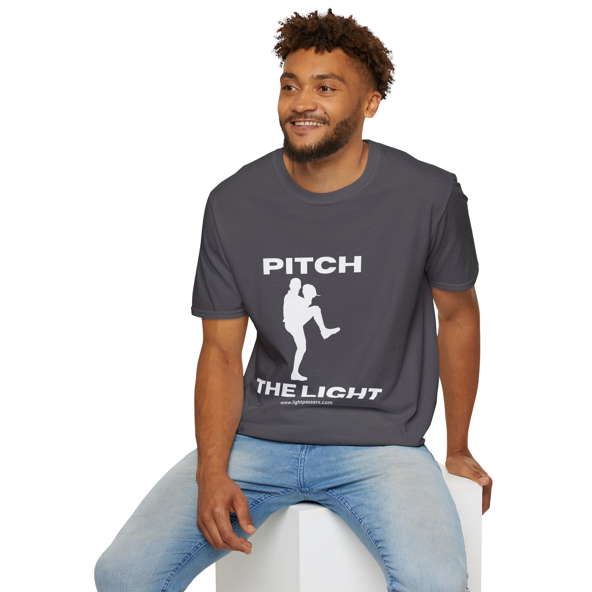 A man in a soft-style unisex t-shirt, sitting on a cube, showcasing casual comfort. Made from 100% cotton with twill tape shoulders for durability and ribbed collar.