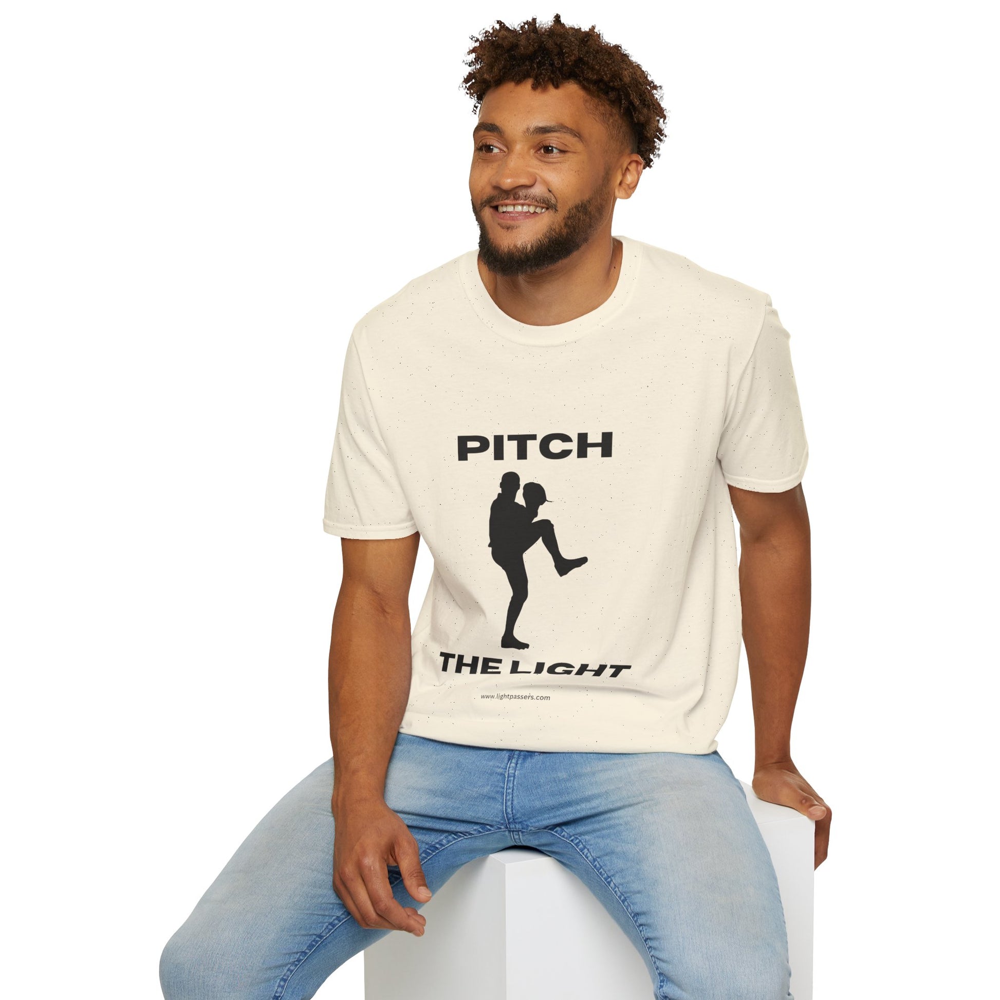 A man in a white PITCH The LIGHT lettering unisex t-shirt, sitting on a cube. Soft 100% cotton tee with twill tape shoulders, no side seams, and ribbed collar. Casual comfort in light fabric.