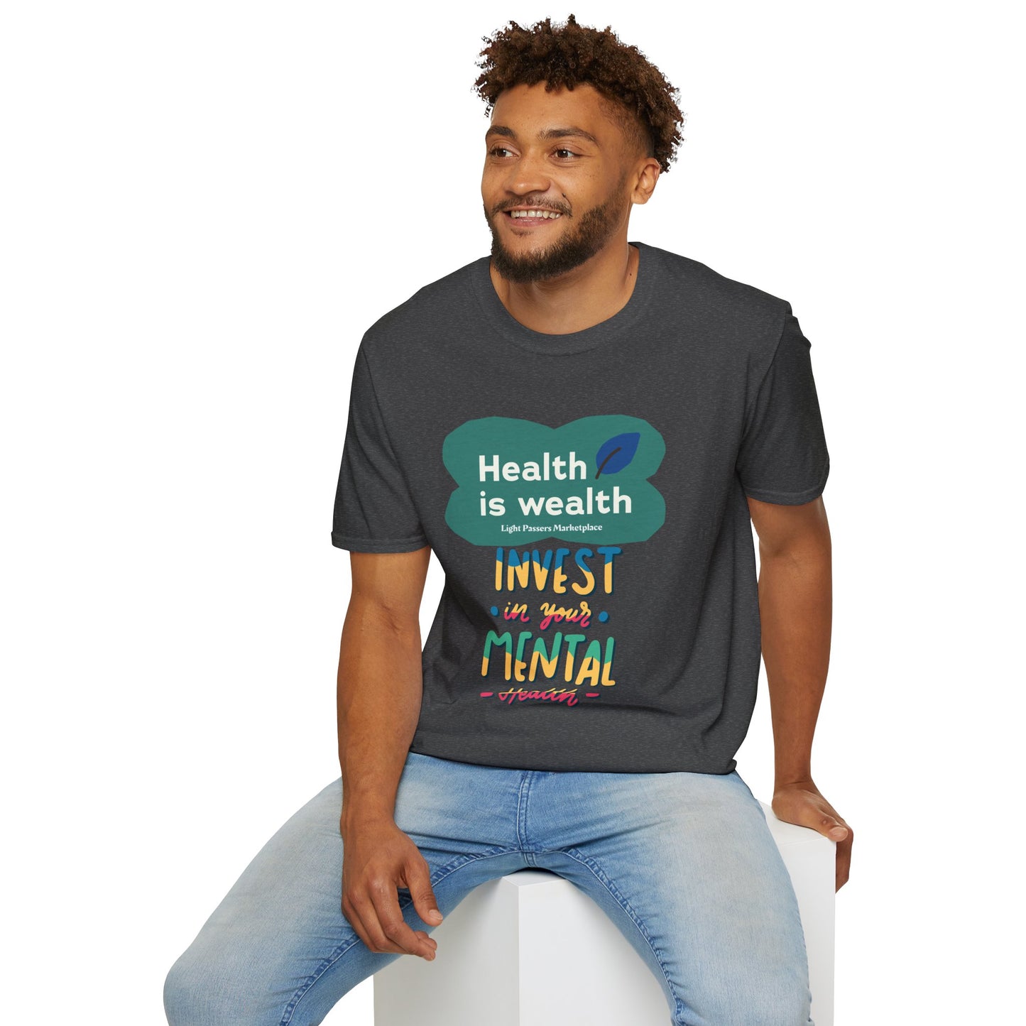 A man in a soft-style unisex t-shirt with text, sitting on a cube. Made of 100% ring-spun cotton, featuring twill tape shoulders and ribbed collar. Ethically sourced and tear-away label for comfort.