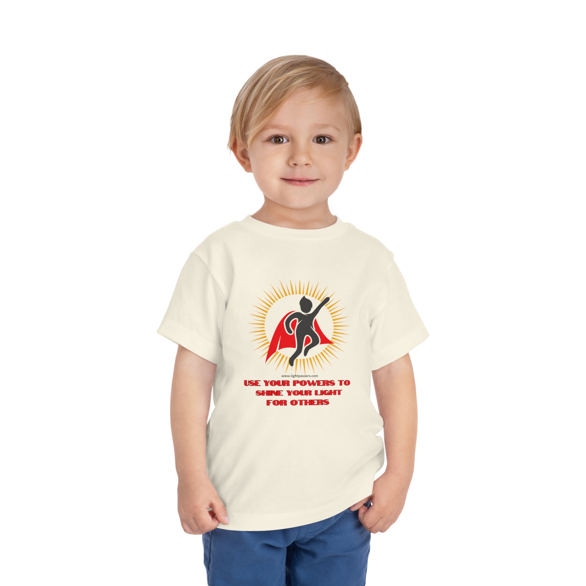 A toddler in a white Use Your Powers t-shirt, featuring a logo with a cape. Made of 100% Airlume combed cotton for comfort.