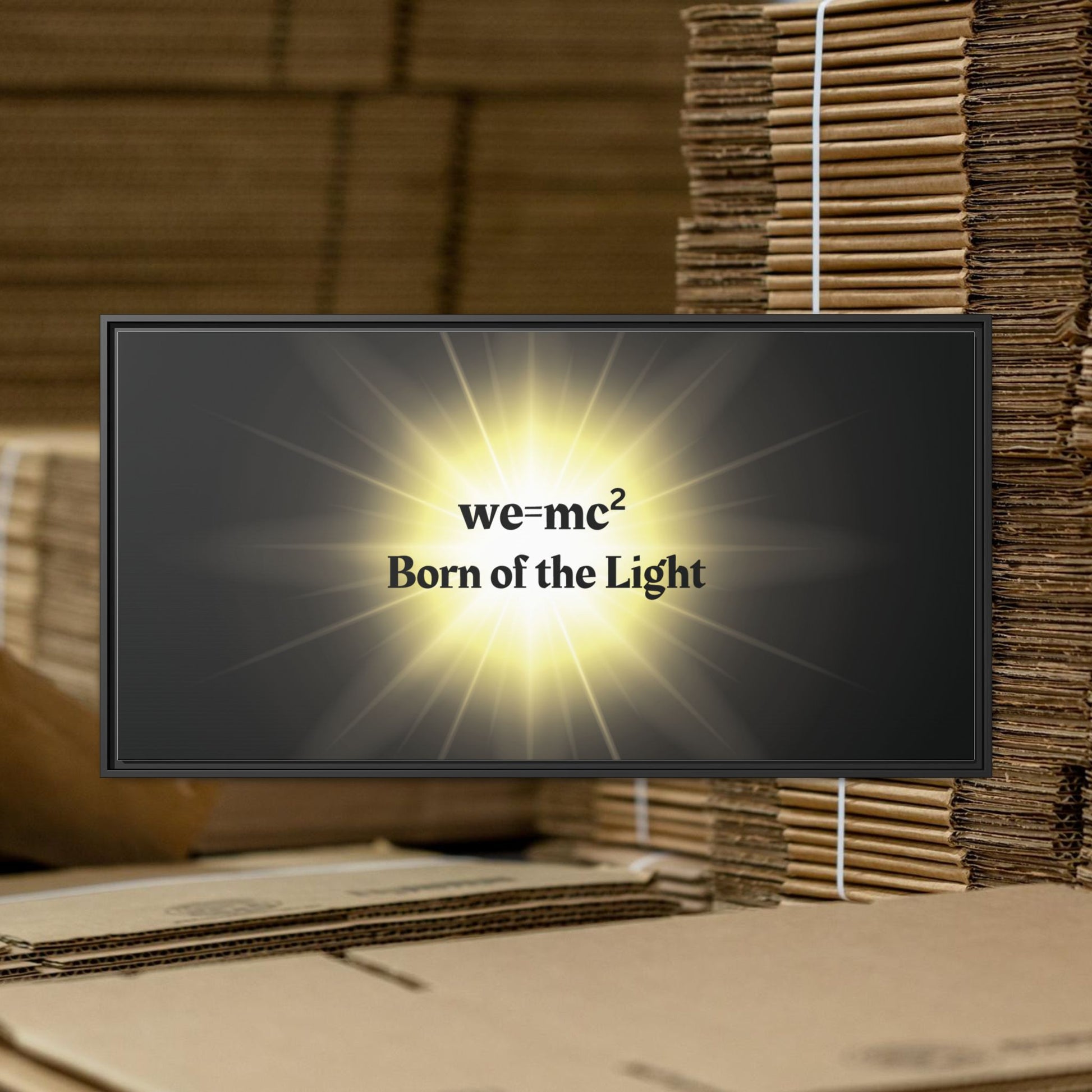 Inspirational Framed Canvas Art - we=mc² Born of the Light, featuring a matte canvas in a black frame, displayed against cardboard boxes.