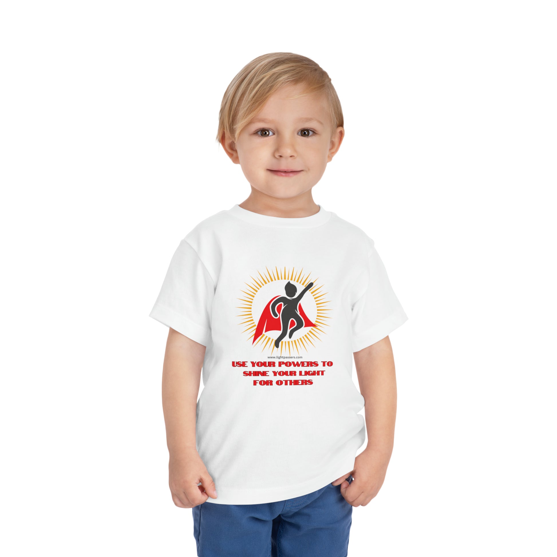 A toddler wearing a white Use Your Powers t-shirt, featuring a logo with a cape. Made of 100% Airlume combed cotton for comfort.