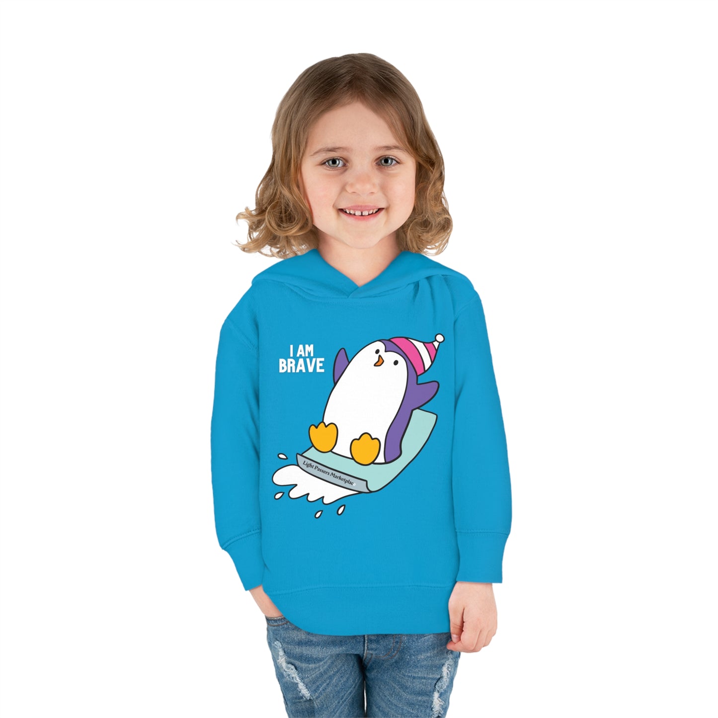 A smiling child in a Brave Penguin Toddler Hoodie with penguin graphic, jersey-lined hood, and side pockets. Durable double-needle stitching for lasting coziness.