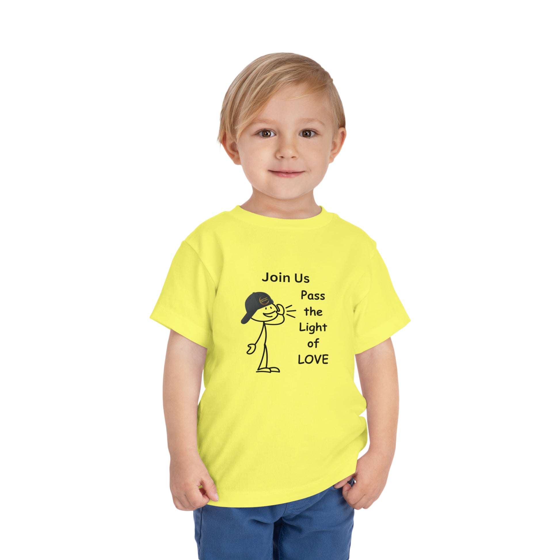 A child in a yellow Call Pass the Light of Love toddler t-shirt, featuring a stick figure with a hat, close-up of blue pants, and a yellow smiley face. 100% Airlume combed cotton tee with tear-away label.