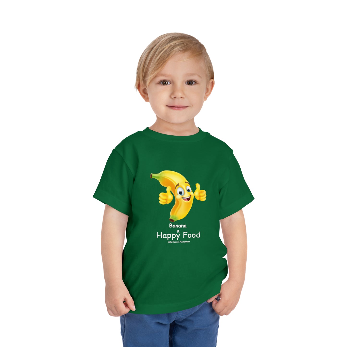 A toddler in a green shirt smiles, a cartoon banana gives a thumbs up. Bella Canvas tee, 100% Airlume cotton, tear-away label.