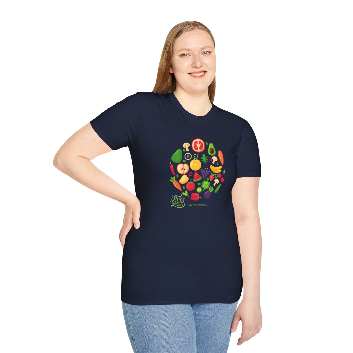 A woman in a Live Healthy Unisex T-Shirt with a fruit design, paired with blue jeans, posing with a group of fruits and vegetables. Made of soft 100% cotton, featuring twill tape shoulders and ribbed collar.