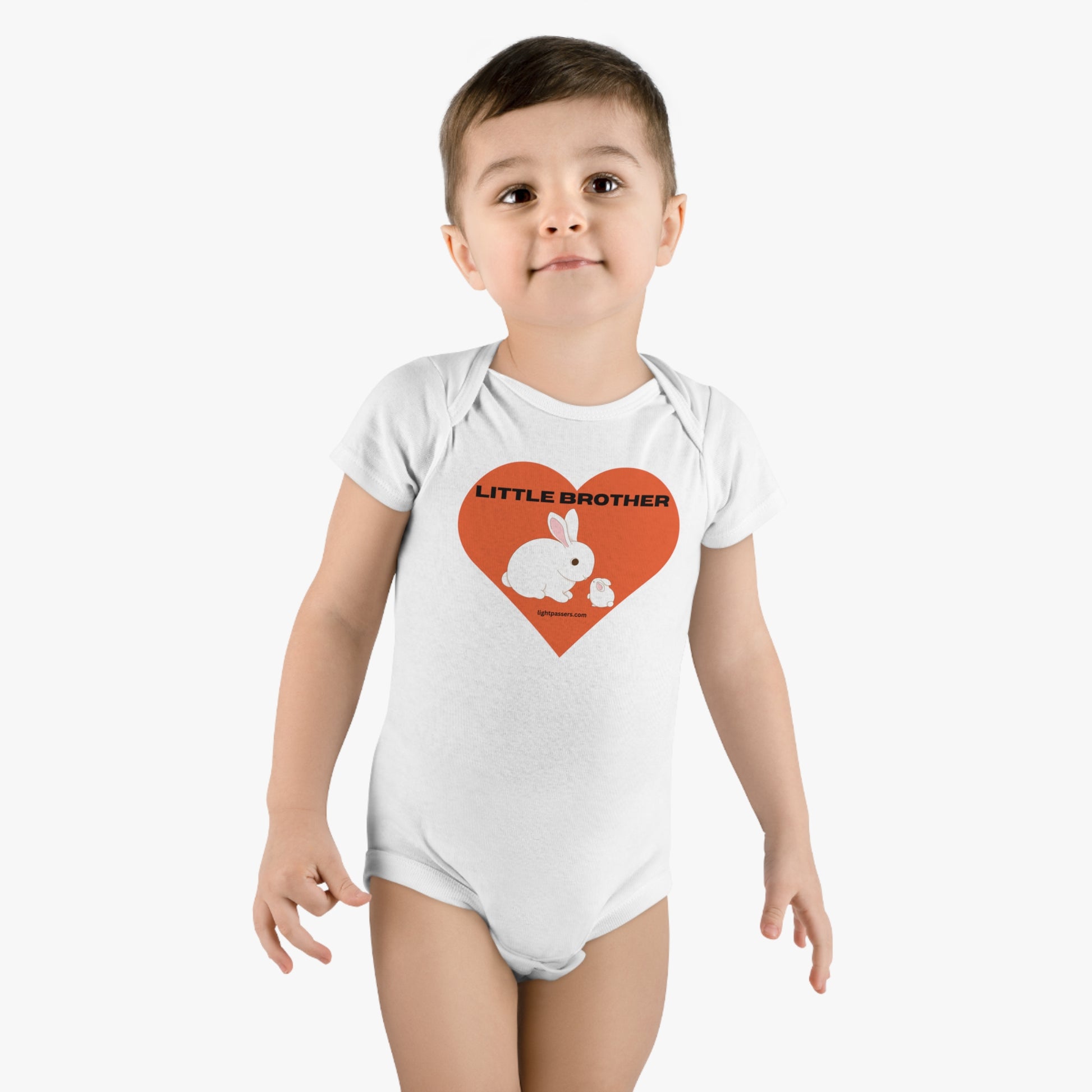 A baby in a white Little Brother Onesie Organic Baby Bodysuit with heart and rabbit prints, made of 100% cotton rib for breathability and elasticity, featuring bottom snap closure for quick changes.