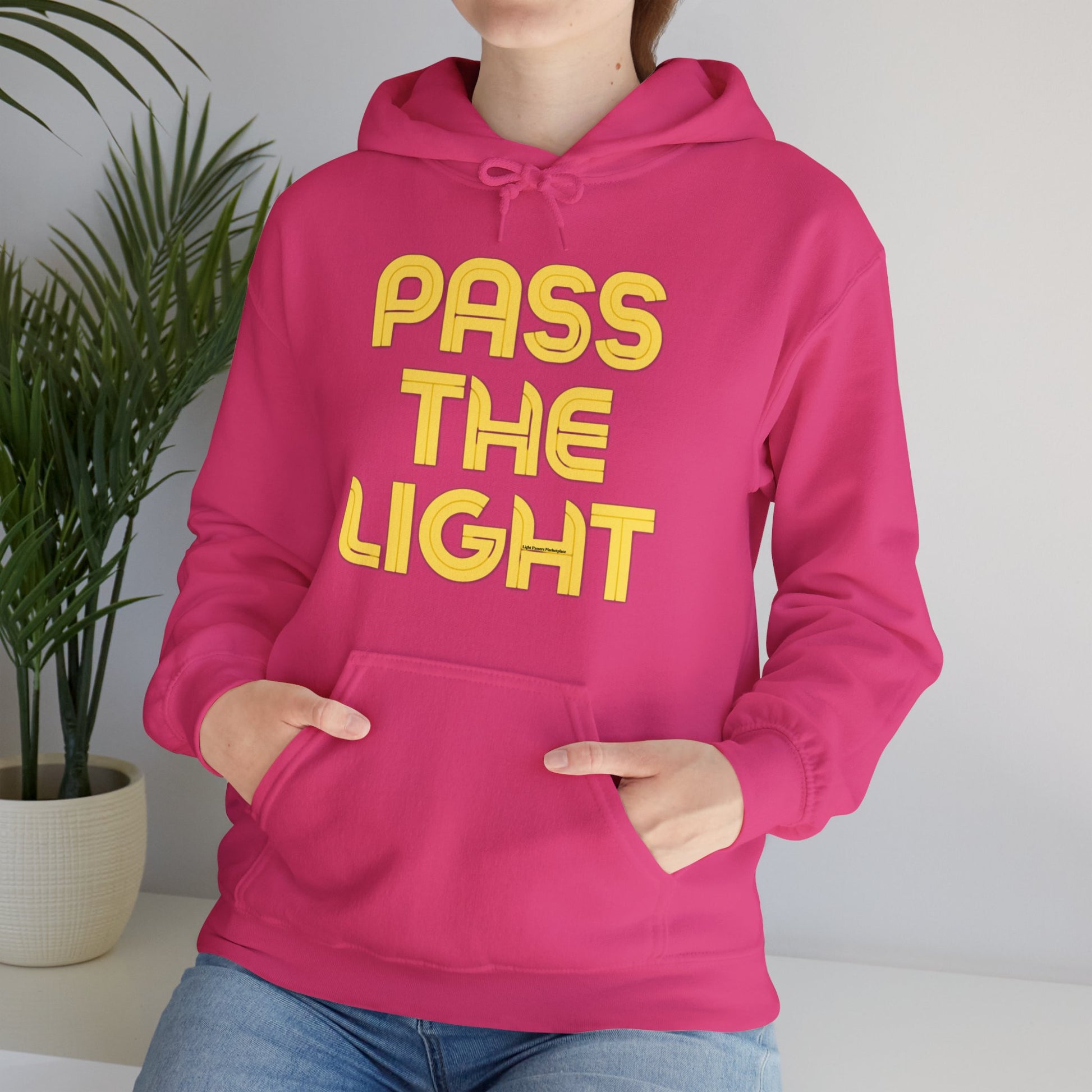 A person in a pink hooded sweatshirt with a kangaroo pocket and drawstring, made of 50% cotton and 50% polyester for warmth and comfort.