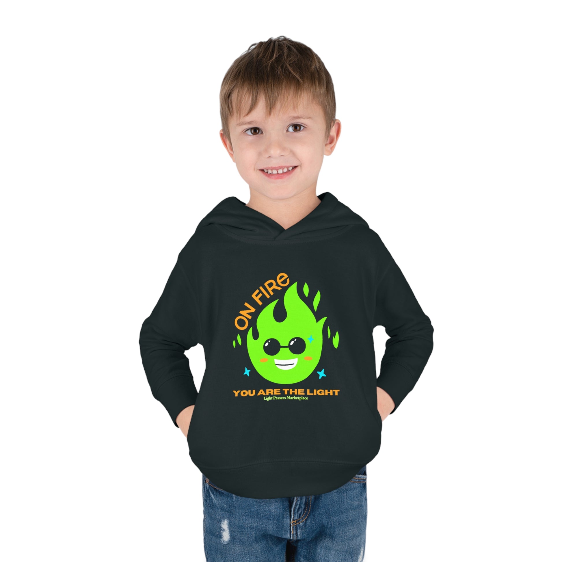 A toddler in a black hoodie with a green flame and yellow text design, featuring side seam pockets and cover-stitched details for durability and comfort.