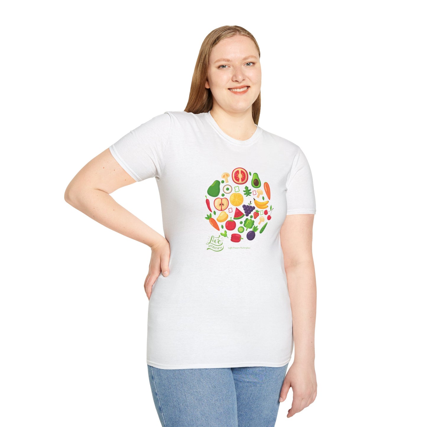 A woman in a white shirt with a fruit design, smiling, showcasing the Live Healthy Unisex T-Shirt. Close-up of jeans and fruits complement the casual, comfortable 100% cotton tee with twill tape shoulders for durability.