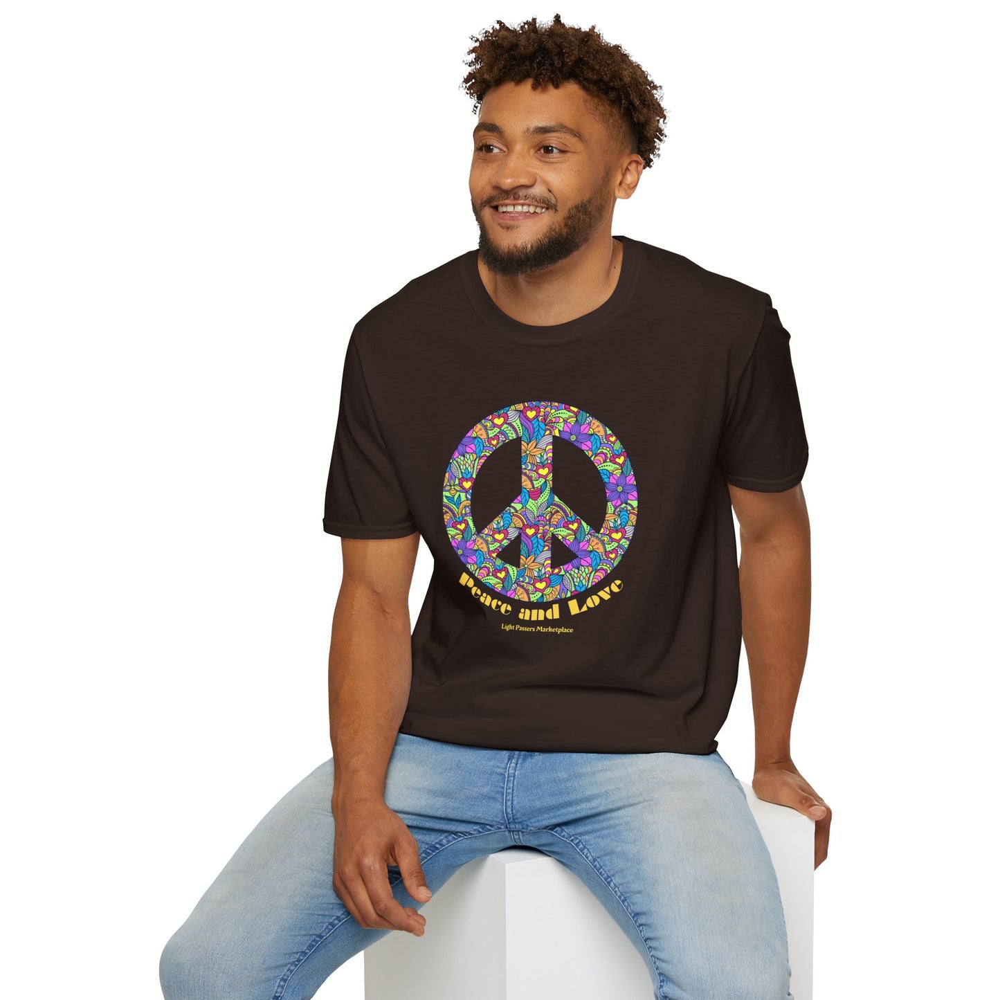 A man in a Peace sign with flowers Unisex T-shirt, sitting on a cube. Soft 100% cotton tee with twill tape shoulders, no side seams, and ribbed collar. Ethically made and Oeko-Tex certified.