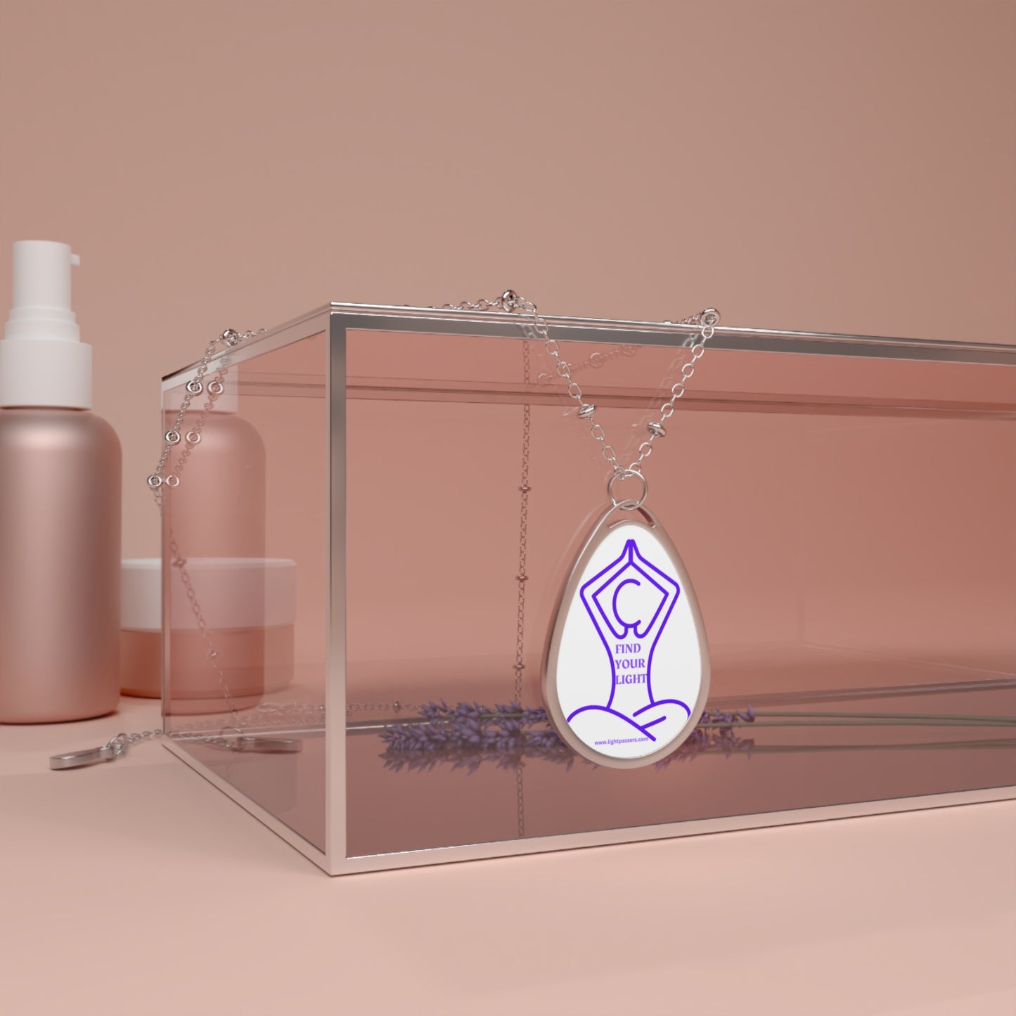 Silver necklace with an ellipse pendant featuring a yoga pose, inscribed 'Find Your Light', displayed in a glass box with a lavender flower.