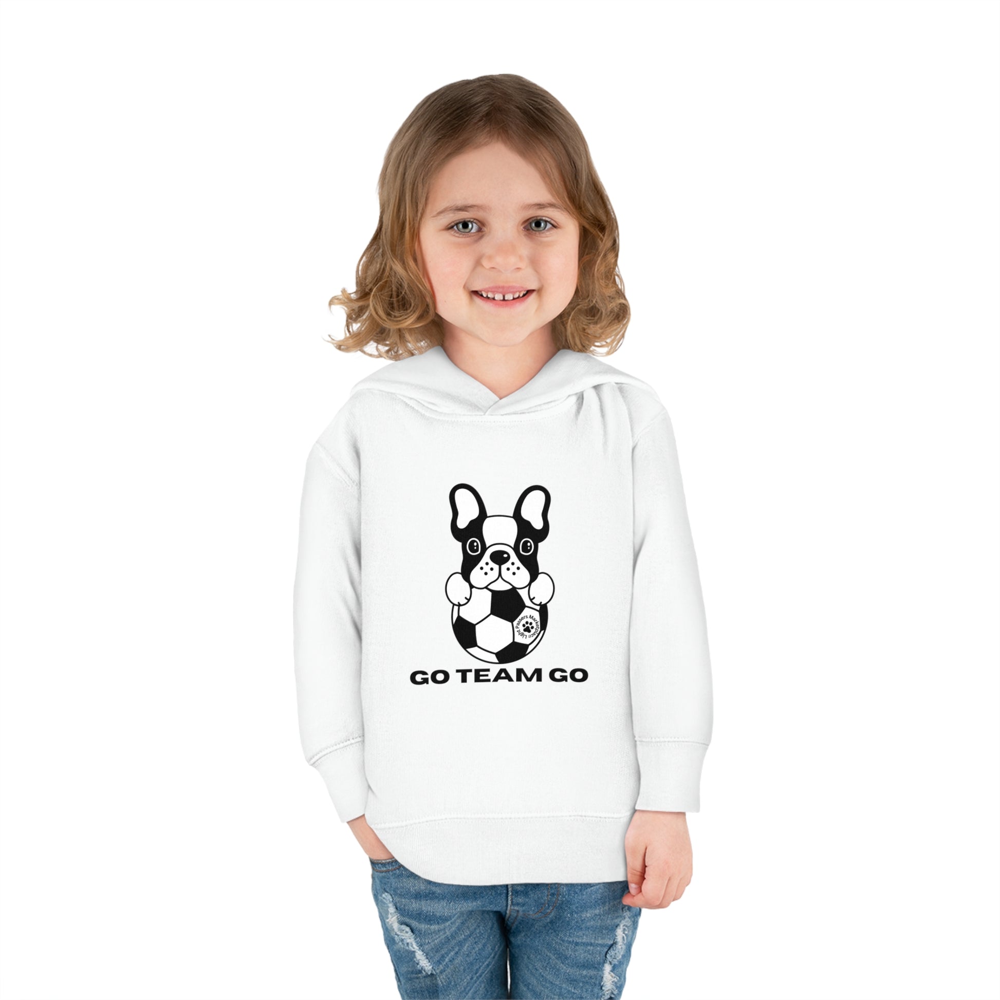 A smiling girl in a Soccer Dog Go Team Go Toddler Hooded Sweatshirt with a dog design, showcasing jersey-lined hood, cover-stitched details, and side seam pockets for comfort and durability.