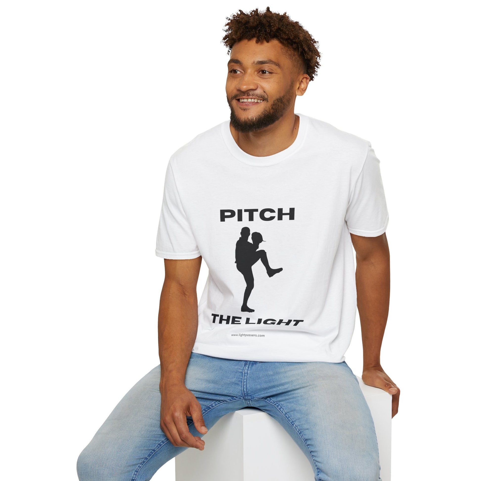 A man in a white shirt sits on a cube, showcasing the PITCH The LIGHT white lettering Unisex T-Shirt. Soft 100% cotton tee with twill tape shoulders and no side seams.