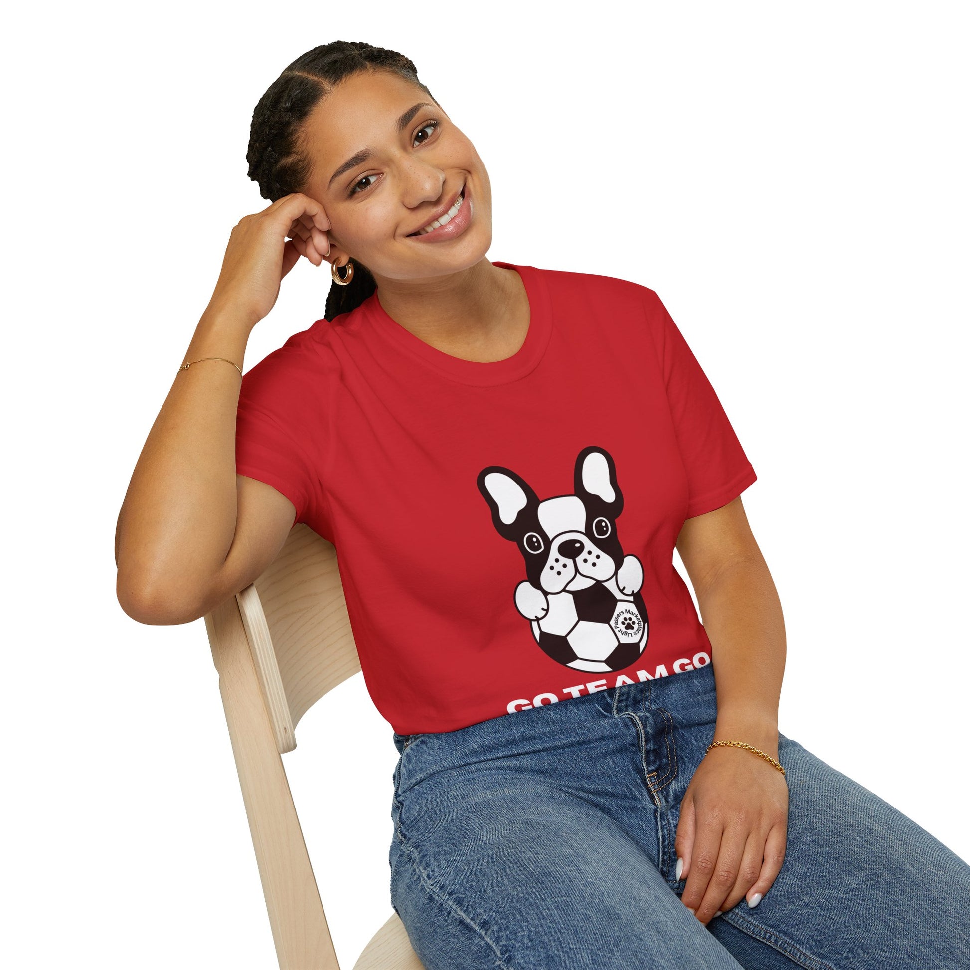 A woman in a red shirt smiles, sitting on a chair with a dog holding a football. Unisex Soccer Dog T-Shirt: 100% cotton, twill tape shoulders, no side seams, ribbed collar. Ethically made, lightweight, versatile.