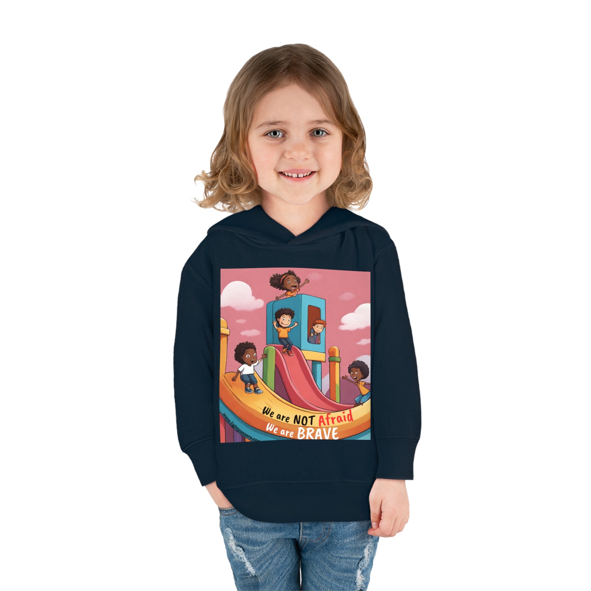 A toddler in a Rabbit Skins hoodie smiles, showcasing comfort and durability. Jersey-lined hood, cover-stitched details, and side seam pockets ensure lasting coziness.