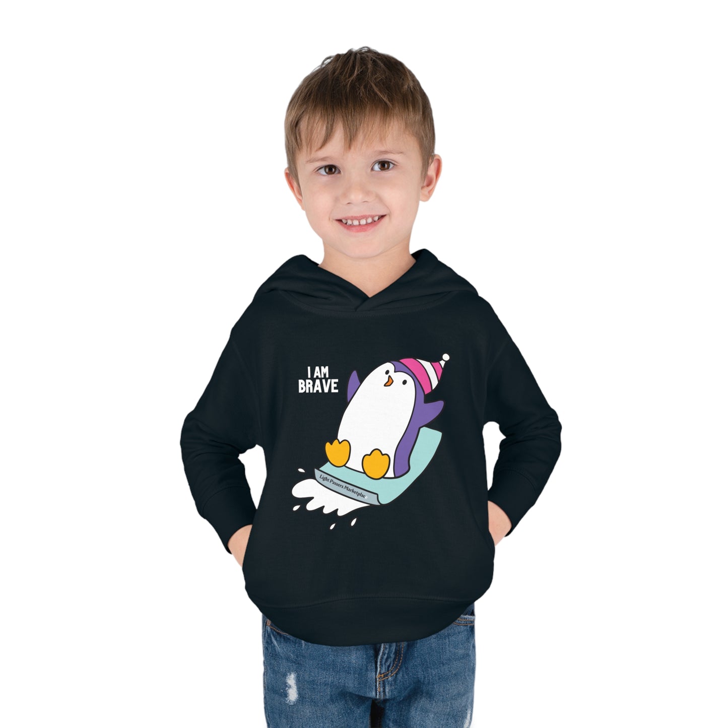A smiling boy in a Brave Penguin Toddler Hooded Sweatshirt with penguin design, jersey-lined hood, and side seam pockets for cozy durability.