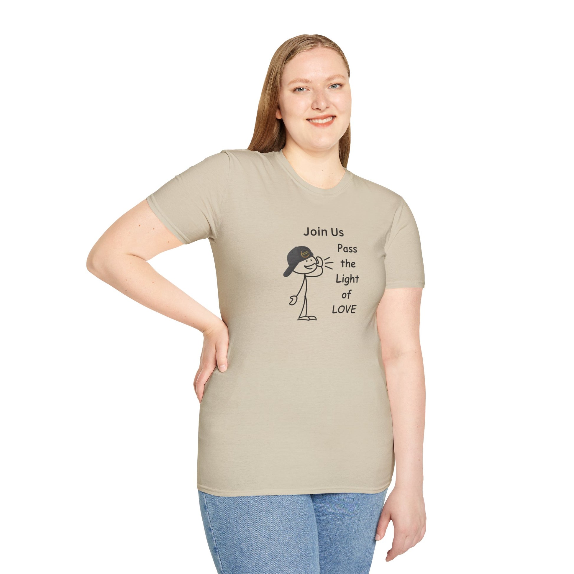 A woman in a tan shirt smiles, posing for a picture in a Join Us Pass the Light of Love Unisex T-shirt. Close-up of blue jeans and a cartoon character with a hat.