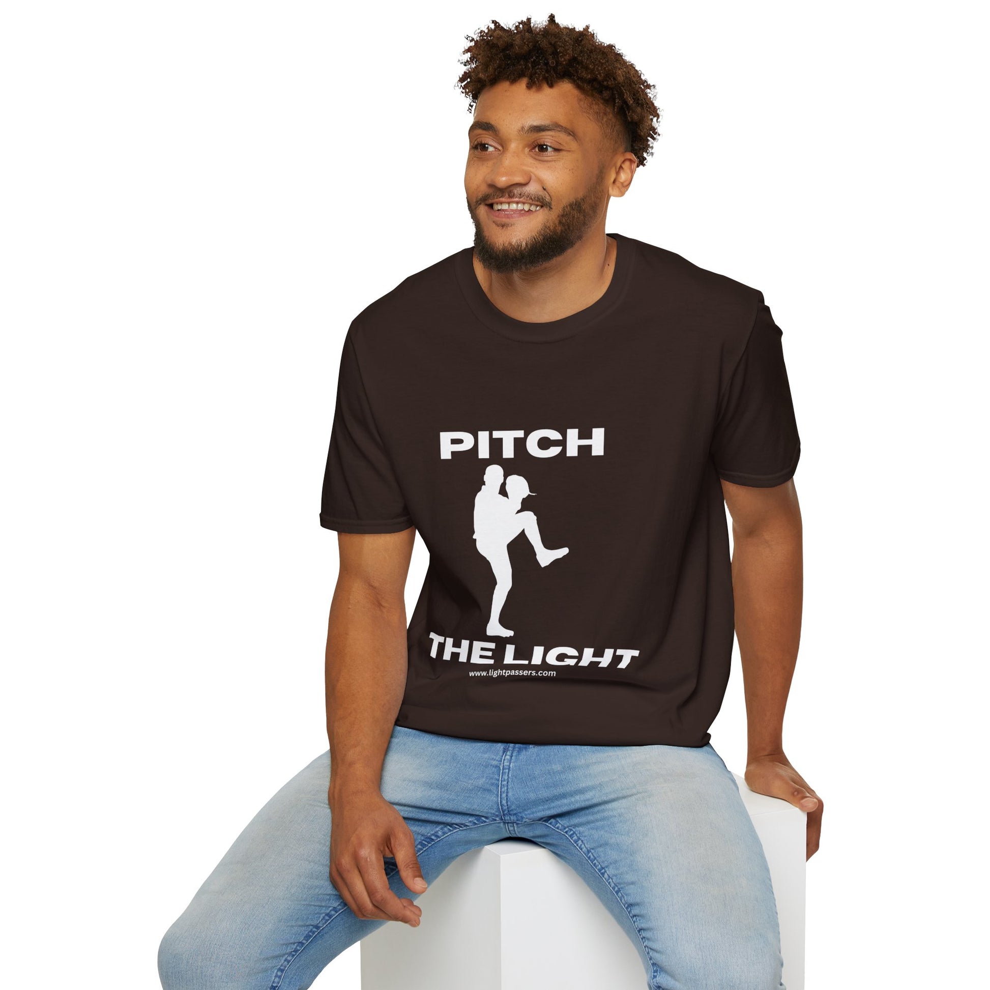 A man in a soft-style unisex t-shirt, sitting on a cube, showcasing casual comfort. Made of 100% ring-spun cotton, Eurofit, tear-away label, and ribbed collar for durability.