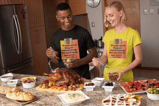 A man and woman around a table of food, man holding potatoes, woman with a spoon. Unisex heavy cotton tee, smooth surface for premium printing. No side seams, tape on shoulders for durability.