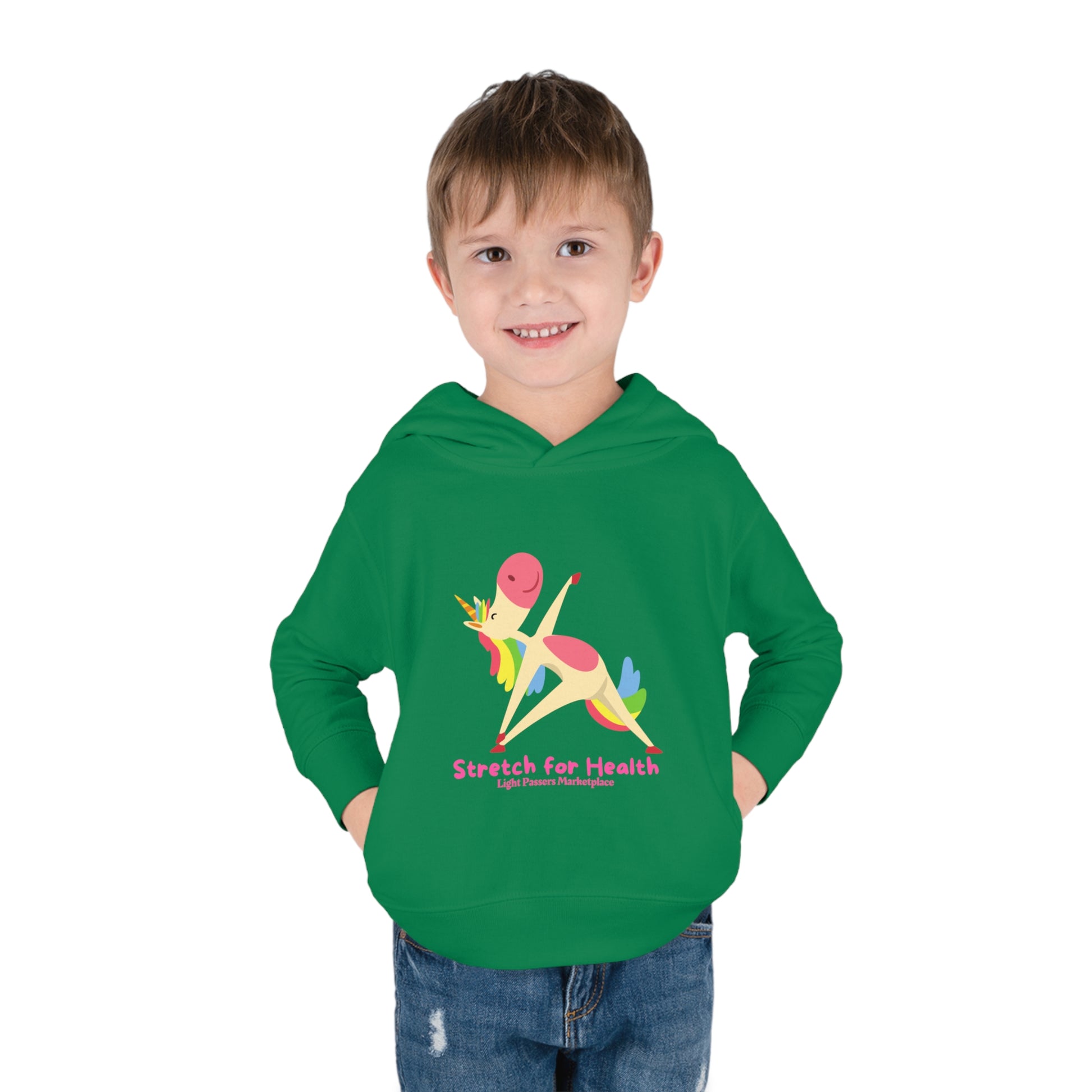 A smiling boy in a Unicorn Stretch Toddler Hooded Sweatshirt with side seam pockets. Jersey-lined hood, cover-stitched details, and durable fabric blend for cozy comfort.