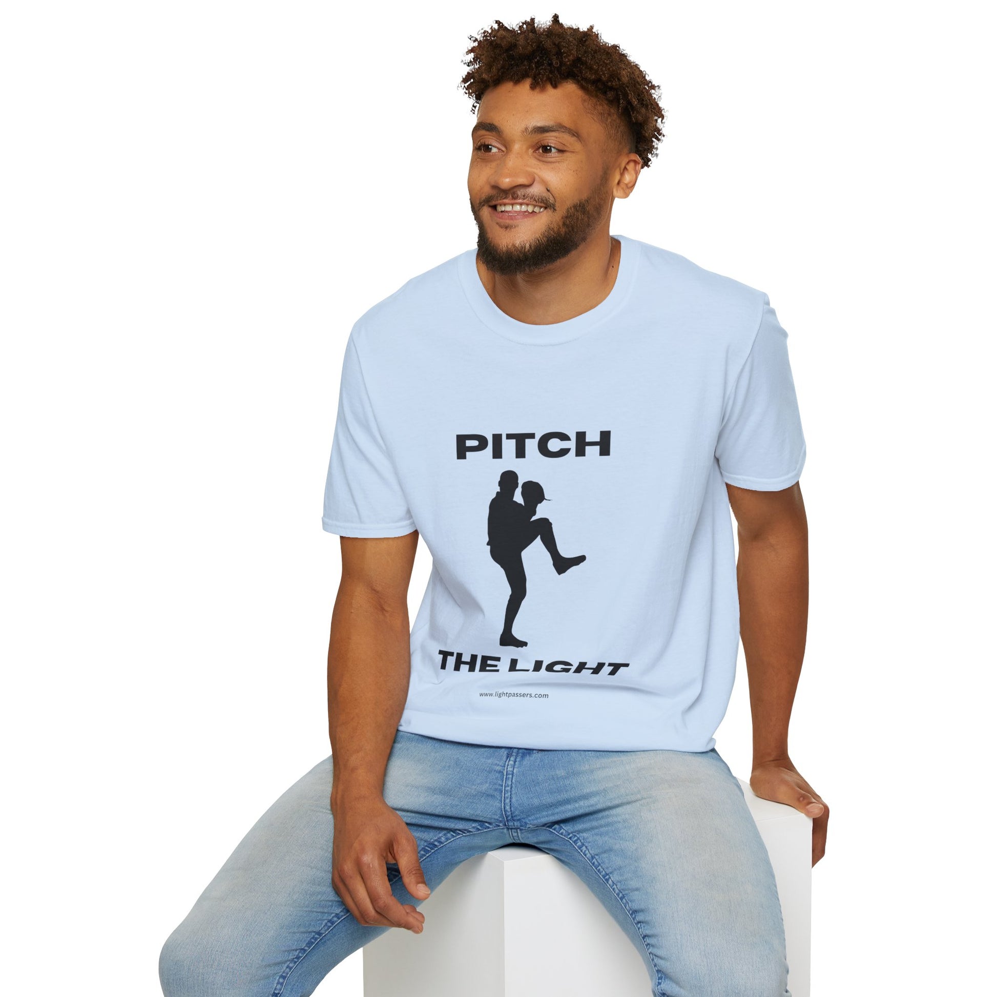 A man in a white PITCH The LIGHT lettering t-shirt, sitting on a cube. Unisex soft-style tee, 100% cotton, twill tape shoulders, no side seams, ribbed collar.