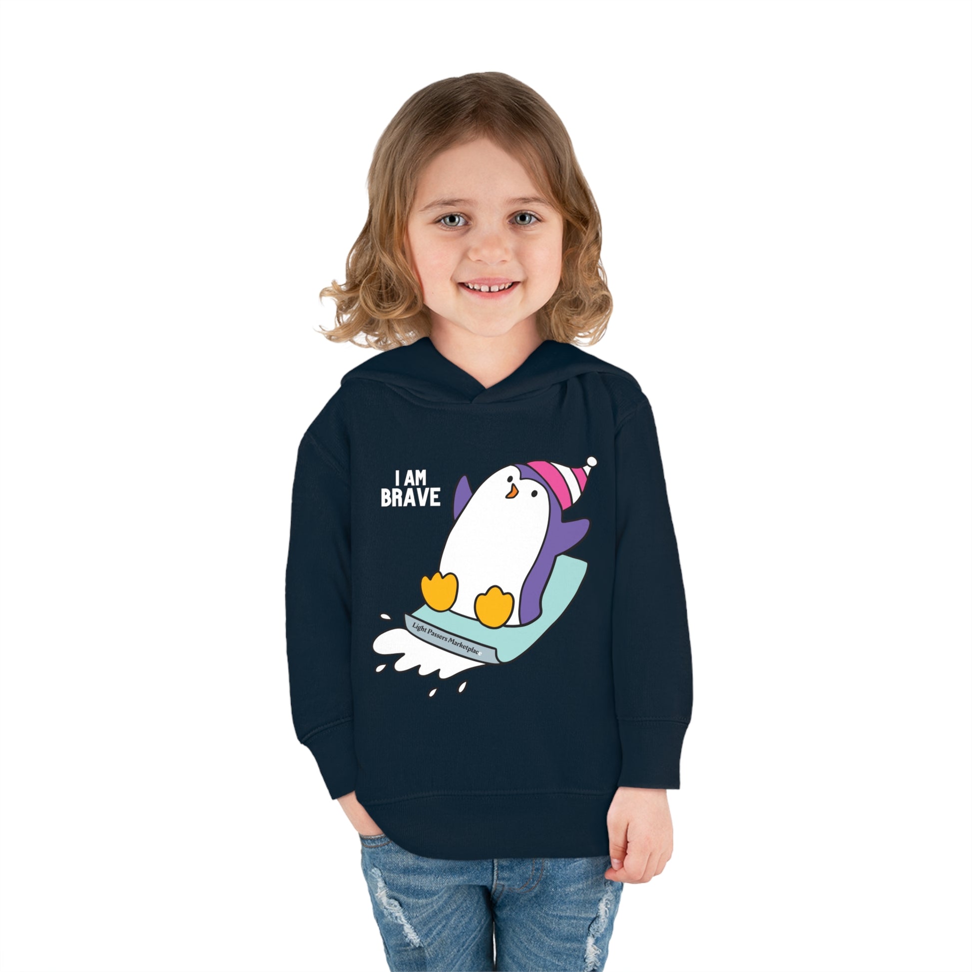 A smiling toddler in a Brave Penguin Toddler Hooded Sweatshirt with jersey-lined hood, cover-stitched details, and side seam pockets for cozy comfort.