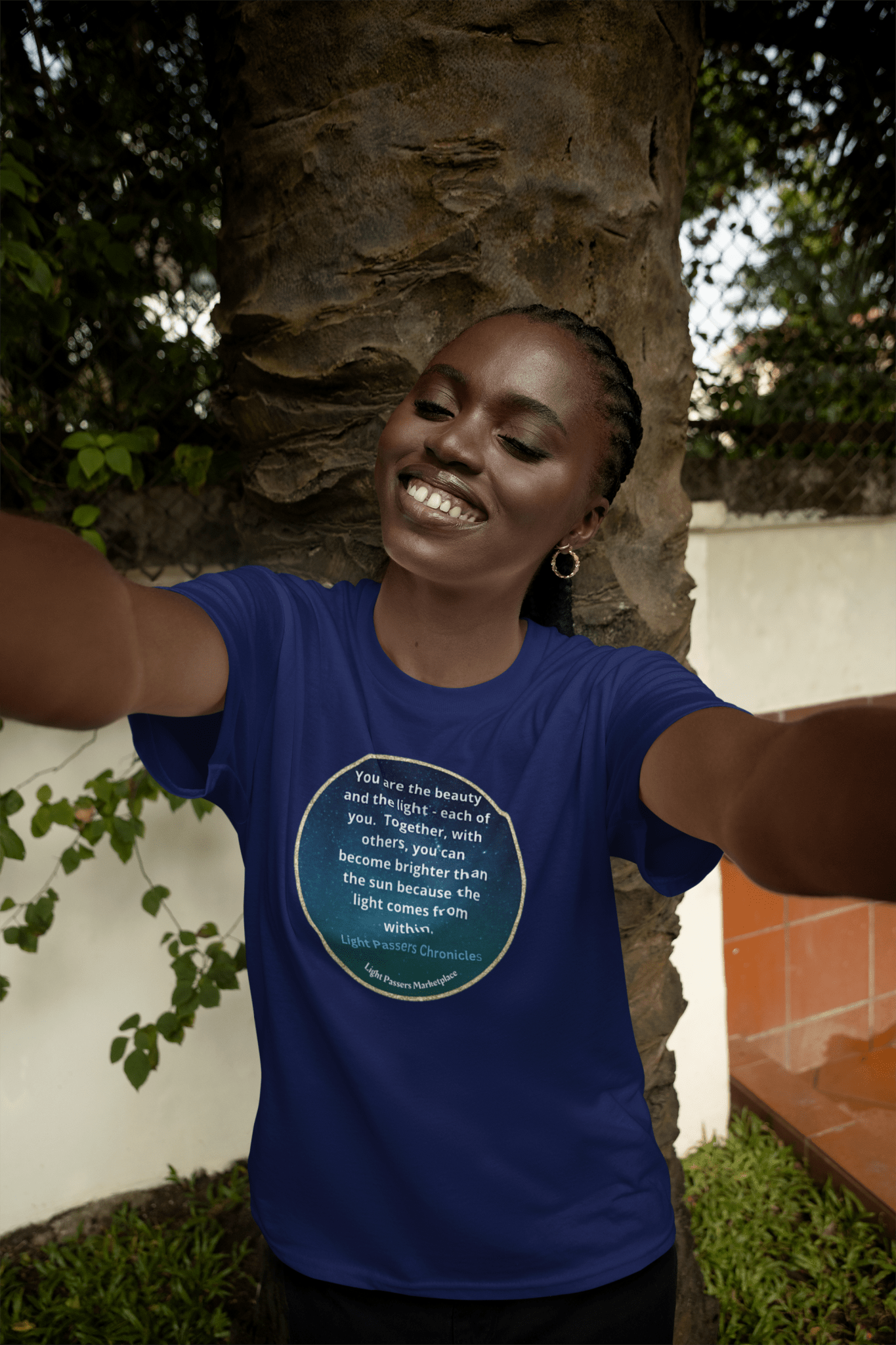 A woman smiles, taking a selfie in a Beauty and the Light Unisex T-shirt. Close-ups show a mouth and arm detail. Outdoor setting with grass and brick wall.