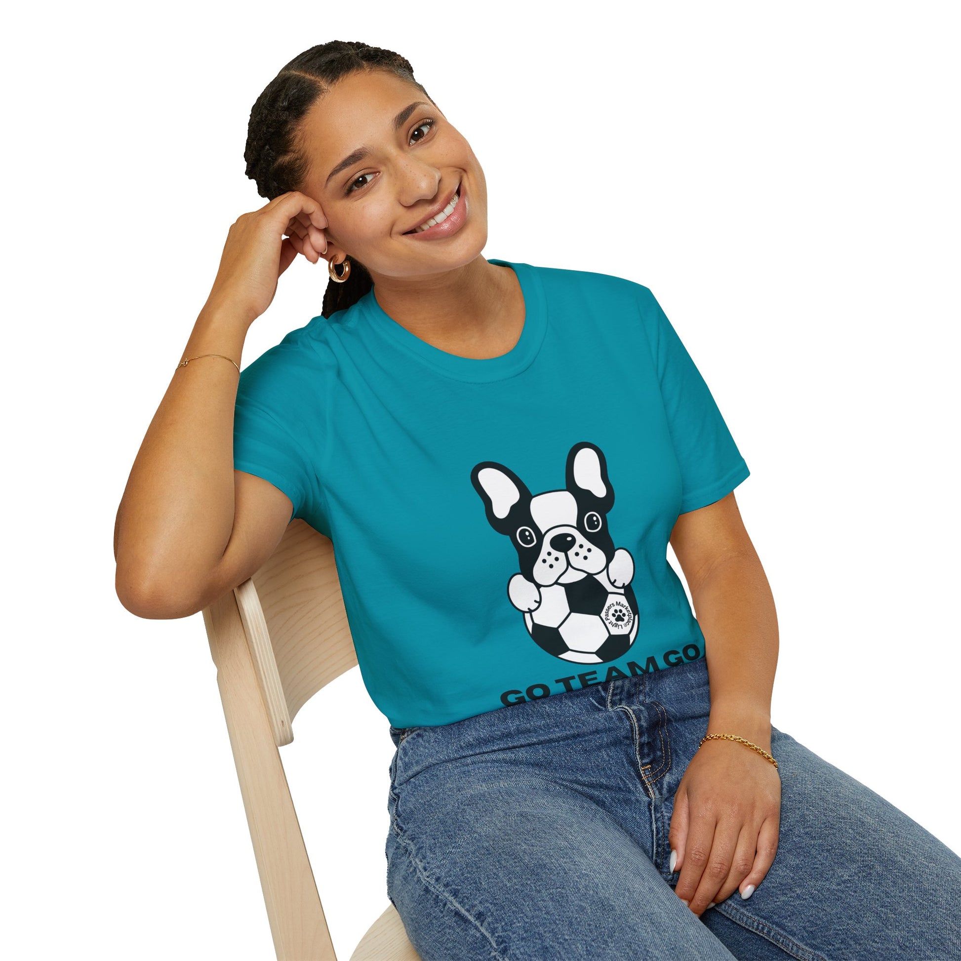 A woman sitting on a chair, smiling, wearing a blue shirt, with a hand on her head, showcasing the Soccer Dog Unisex T-Shirt's casual comfort and 100% ring-spun cotton fabric for versatile style.