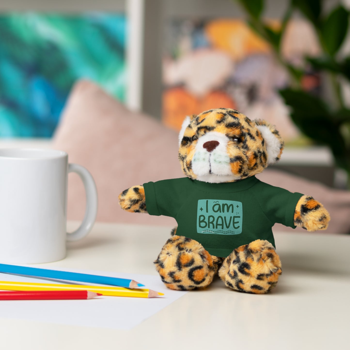Cool Stuff Stuffies stuffed animal, wearing a removable I am Brave tee, displayed on a table. Part of a collection offering six customizable animal designs.