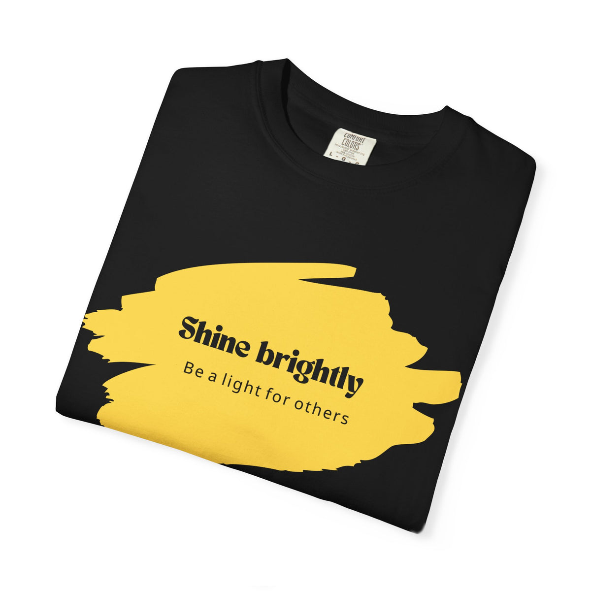Black unisex T-shirt close-up of yellow paint-splash “Shine brightly” graphic