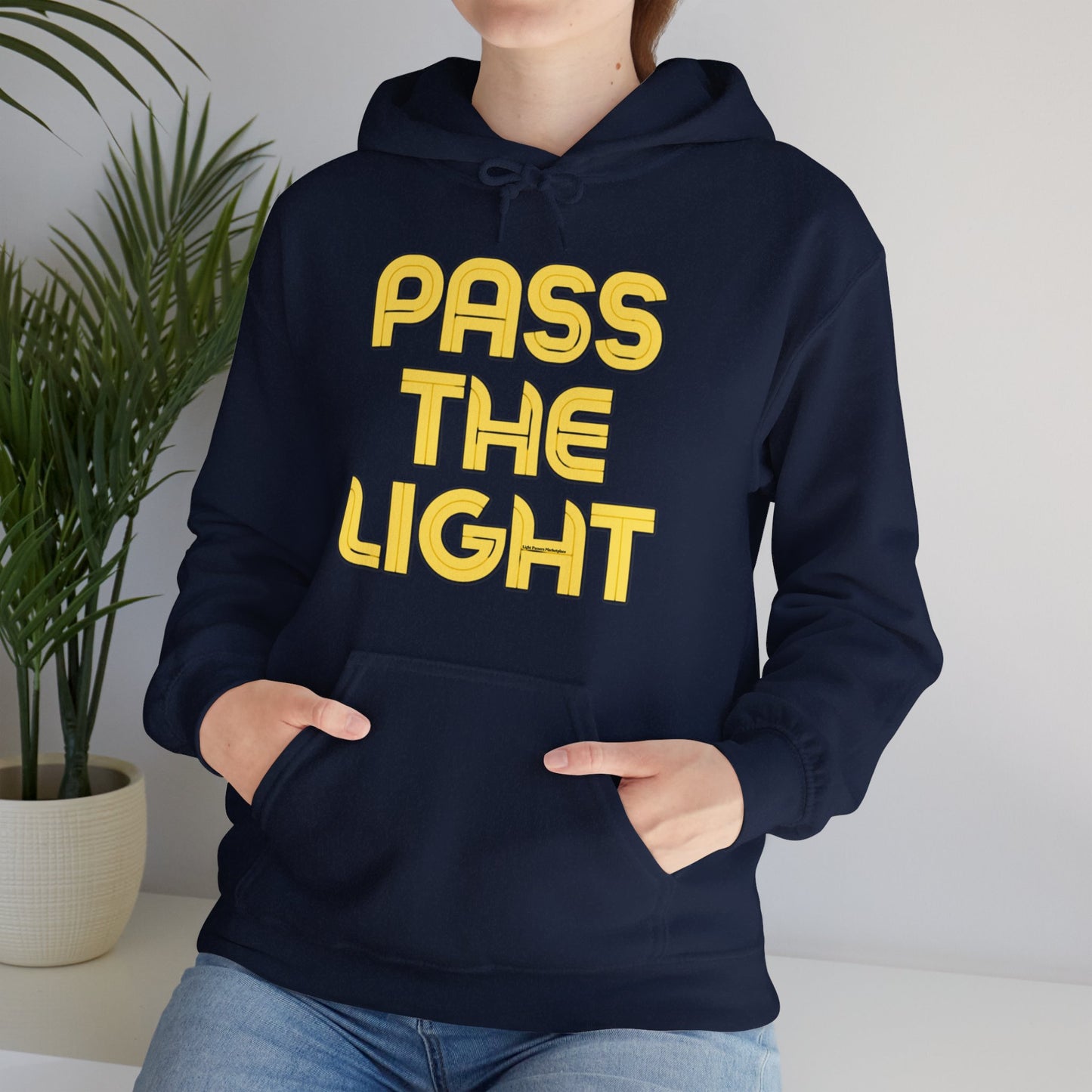 A person in a Pass the Light Unisex Hooded Sweatshirt with a kangaroo pocket and matching drawstring, showcasing a cozy blend of cotton and polyester for warmth and comfort.