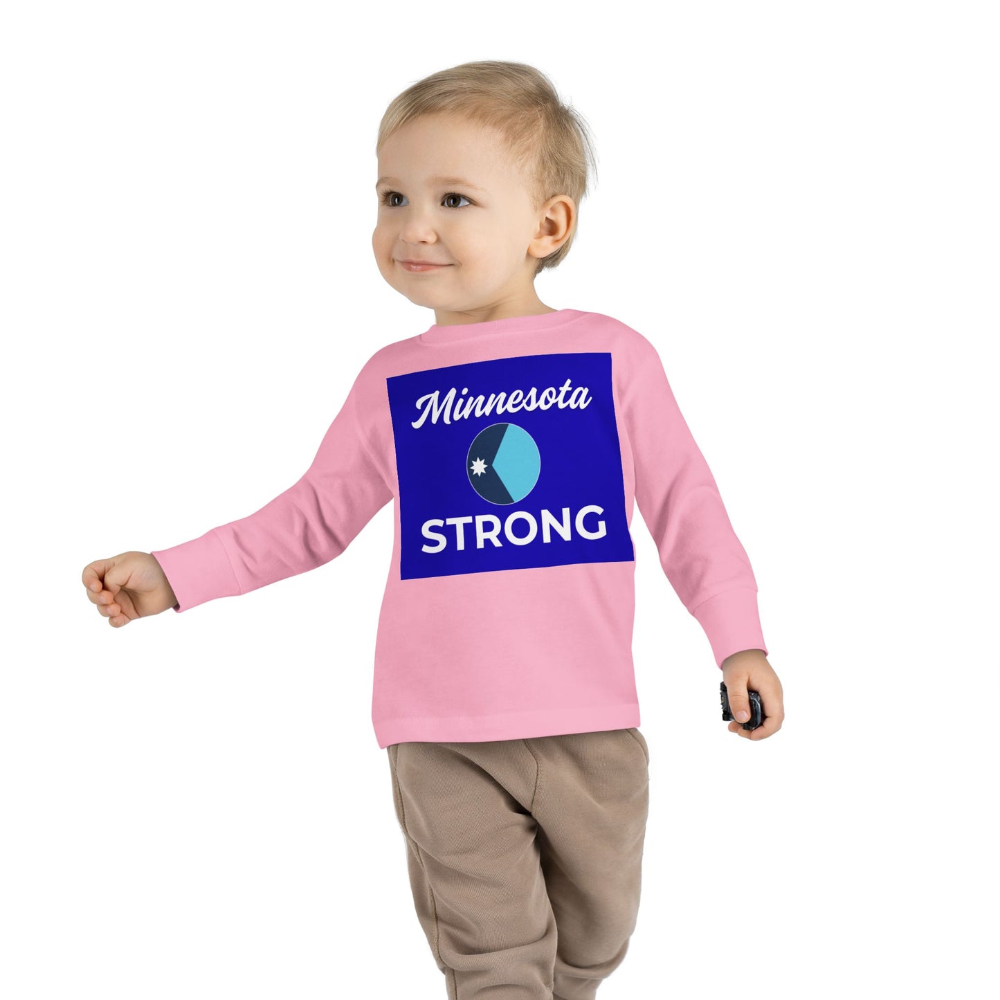 Toddler wearing Minnesota Strong long sleeve tee holds toy car. Shirt symbolizes community pride. Ideal for active play, reflecting Light Passers Marketplace's inspirational ethos.