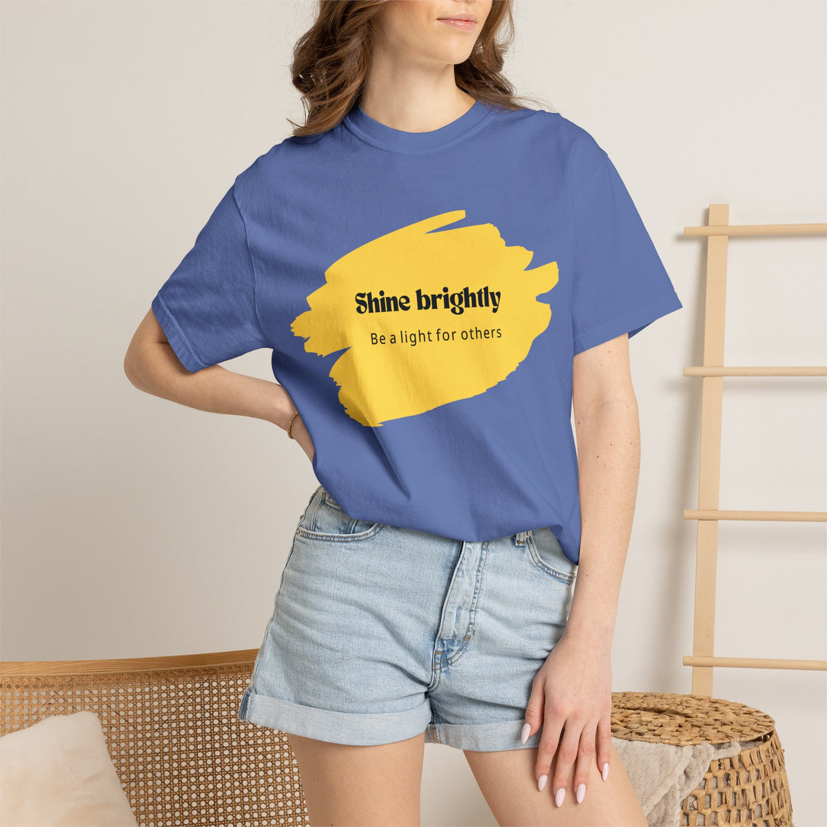 Periwinkle-blue unisex T-shirt worn by model with yellow “Shine brightly” graphic.