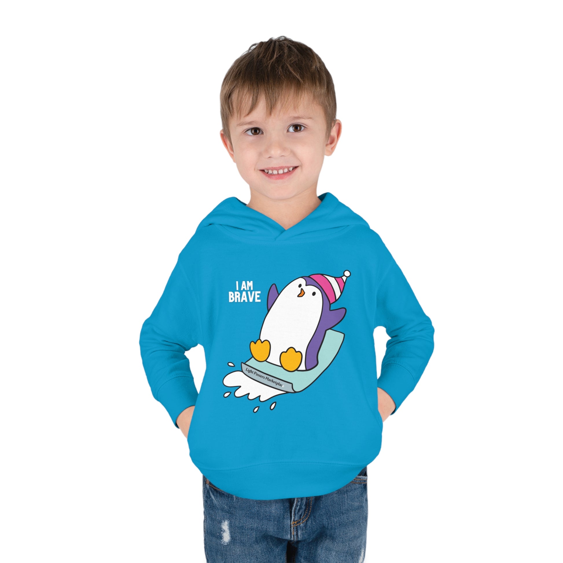 A toddler in a blue Rabbit Skins hoodie with a penguin design, showcasing jersey-lined hood, cover-stitched details, and side seam pockets for cozy durability.