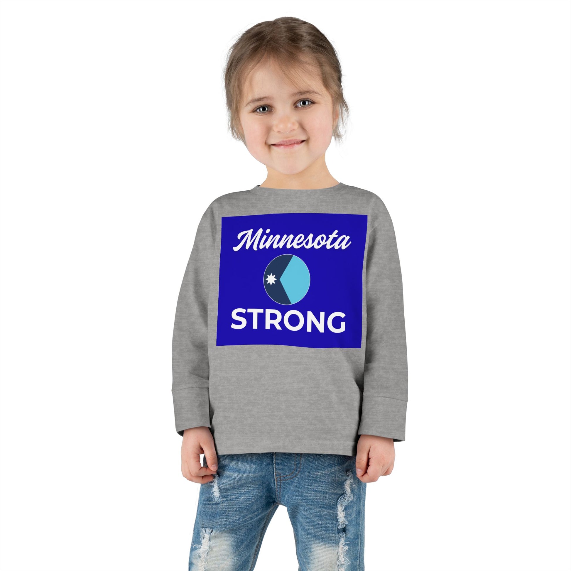 Child wearing Love and Peace The Light Minnesota Strong Toddler Long Sleeve Tee, featuring Minnesota STRONG graphic, exuding community pride. Paired with blue jeans.