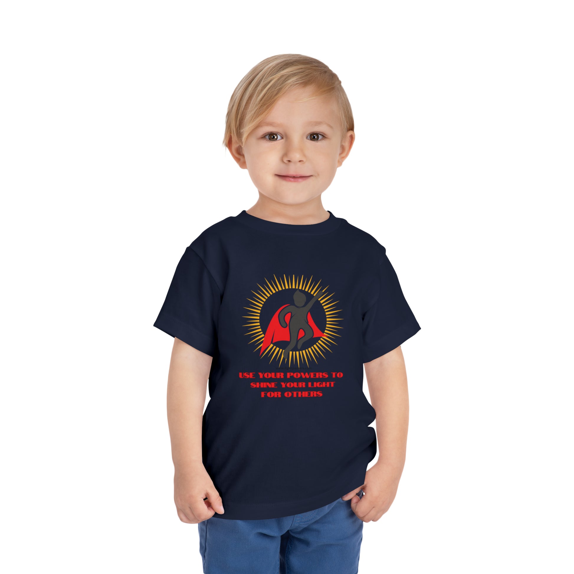 A toddler in a Use Your Powers t-shirt, featuring a superhero logo, on a child-friendly blue top. Made of 100% Airlume combed cotton for comfort.