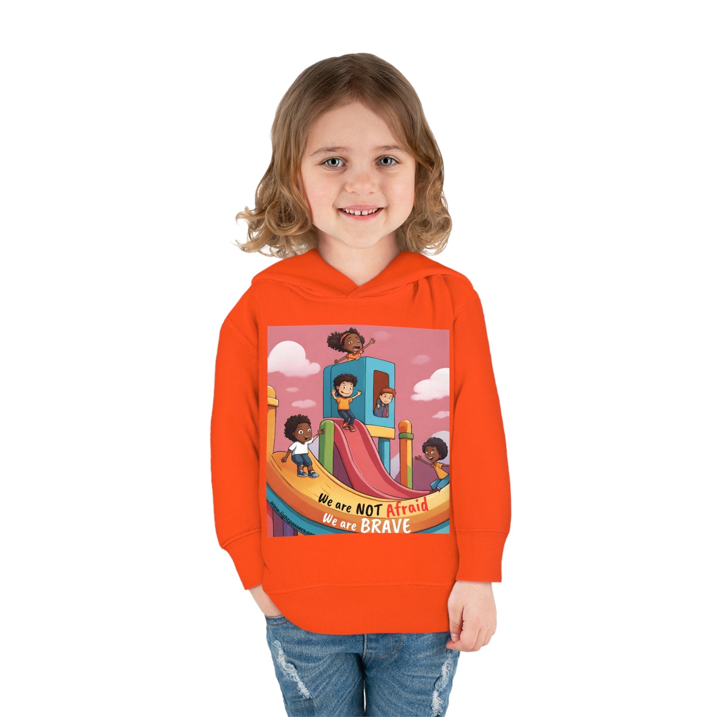 A child in a Rabbit Skins personalized toddler hoodie with a cartoon image, smiling at the camera. Features jersey-lined hood, side-seam pockets, and durable stitching for long-lasting coziness.