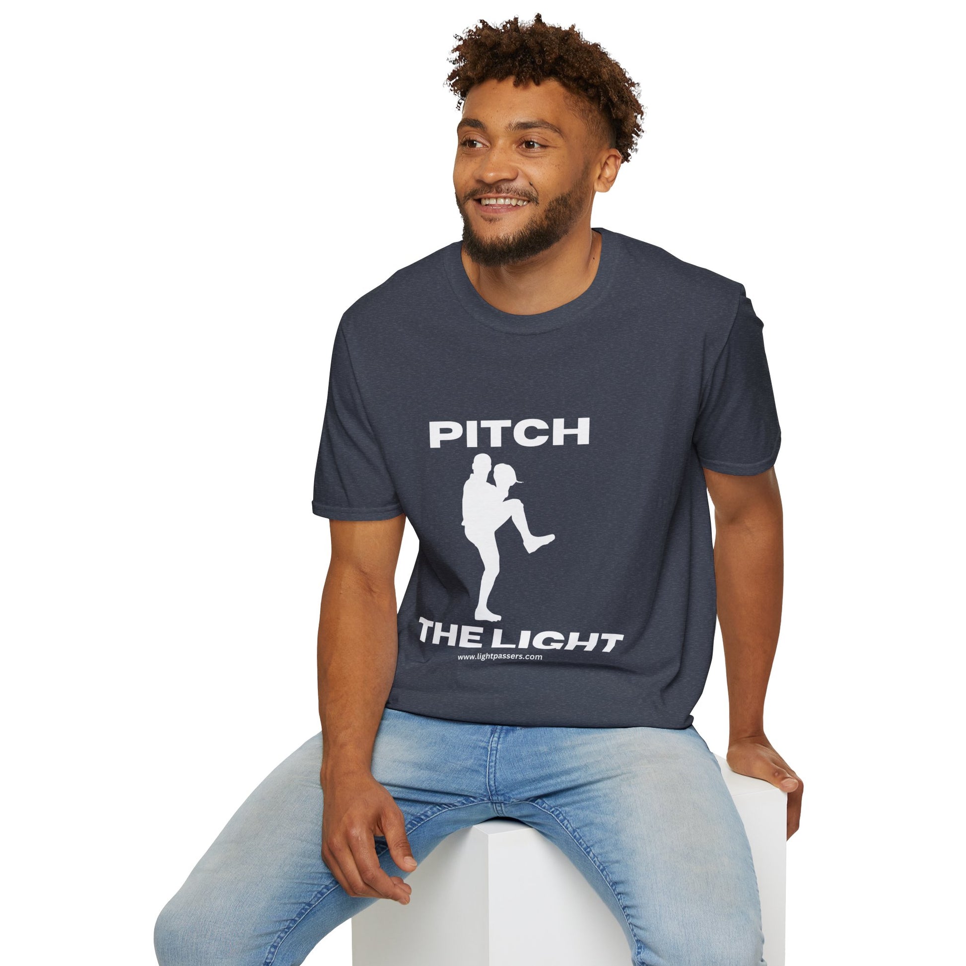 A man in a white PITCH The LIGHT t-shirt, sitting on a cube. Unisex soft-style tee, 100% cotton, twill tape shoulders, no side seams, ribbed collar.