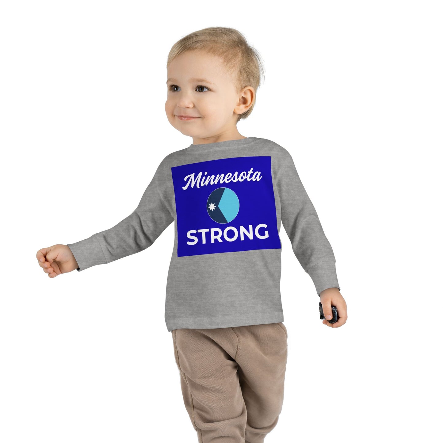 Toddler in grey Minnesota Strong long sleeve from Light Passers Marketplace, showcasing community pride with blue graphic, paired with light brown pants.