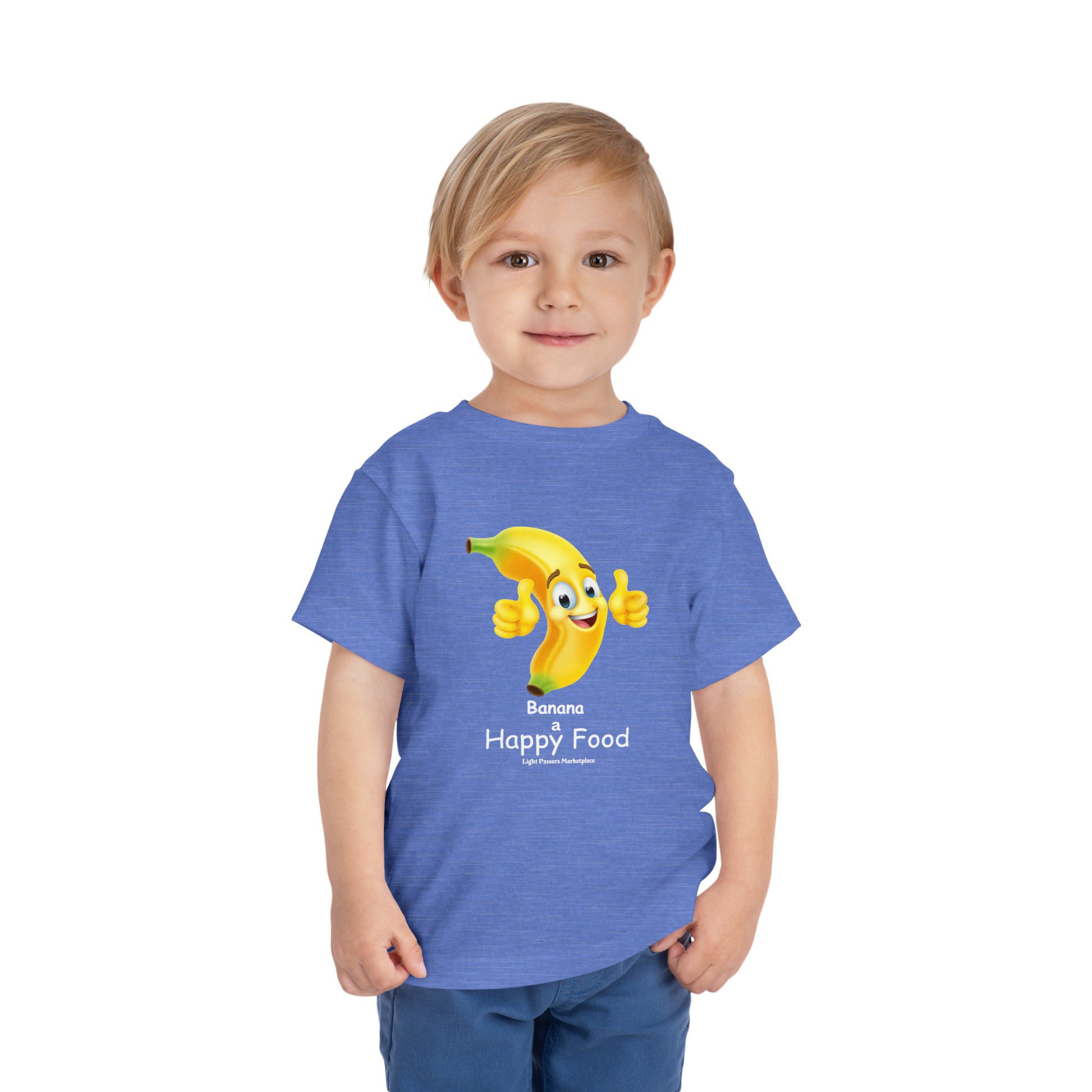 A child in a blue shirt with a cartoon banana giving a thumbs up, showcasing the Banana Happy Food Toddler T-shirt. Made of 100% Airlume combed cotton, tear-away label for comfort.