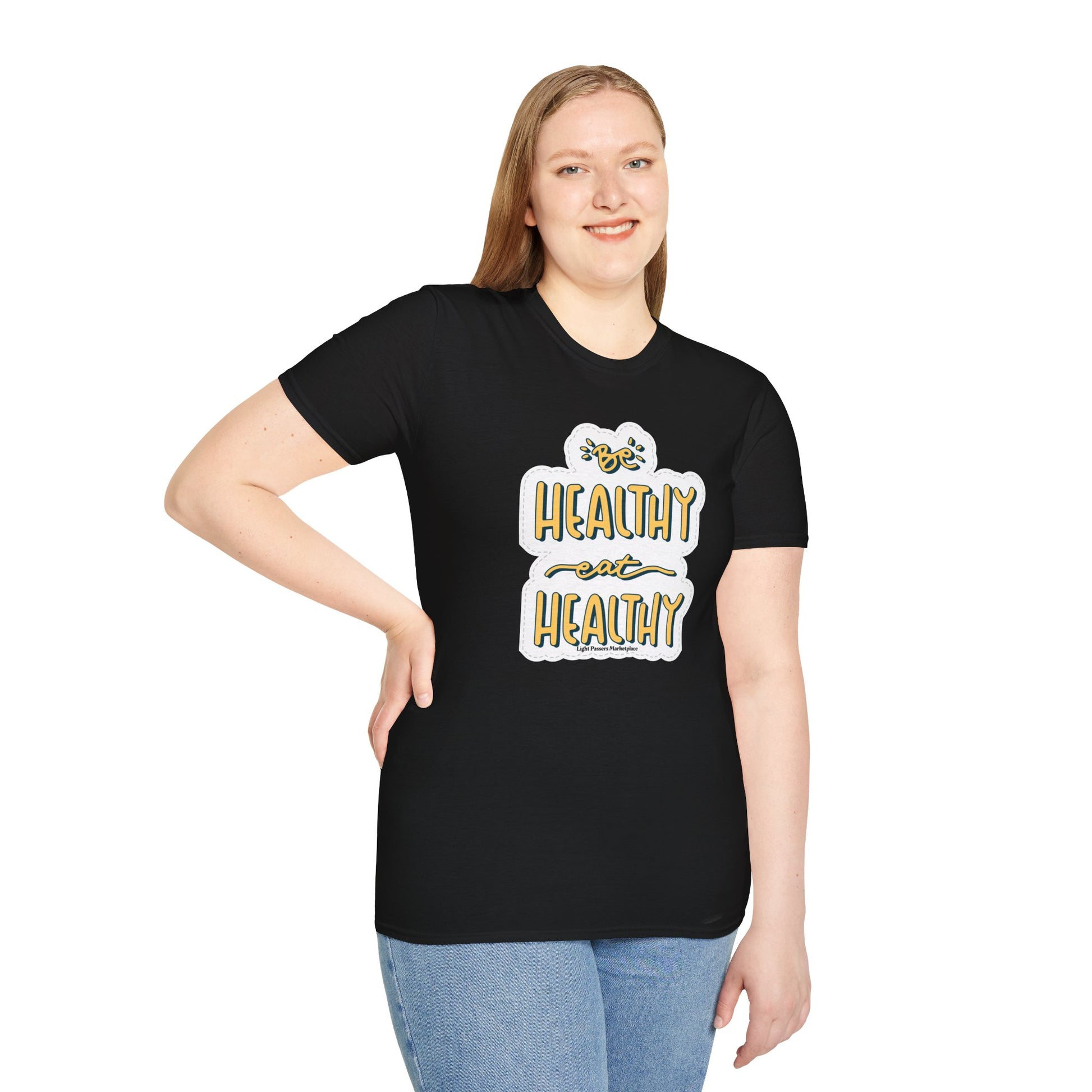 A woman in a black shirt with a white and yellow logo smiles, showcasing the Be Healthy Eat Healthy Unisex T-Shirt. The close-up image highlights the soft, 100% cotton fabric and classic crew neckline for versatile style.