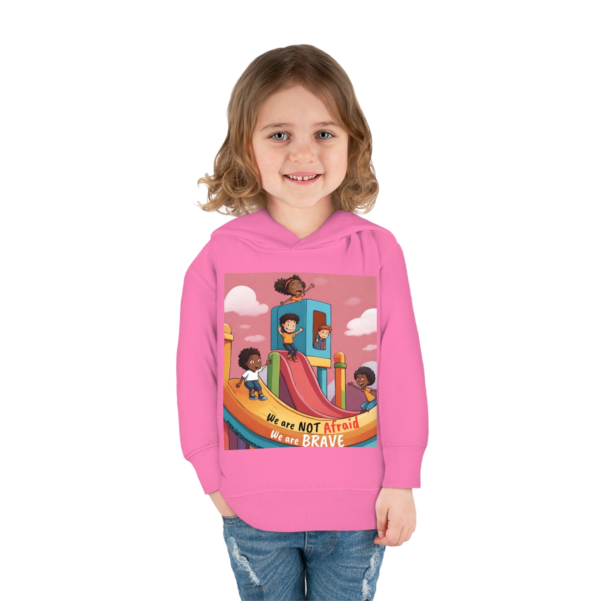 A smiling girl in a Rabbit Skins toddler hoodie with a slide and building print. Features jersey-lined hood, cover-stitched details, side pockets, and durable cotton-poly blend for cozy wear.